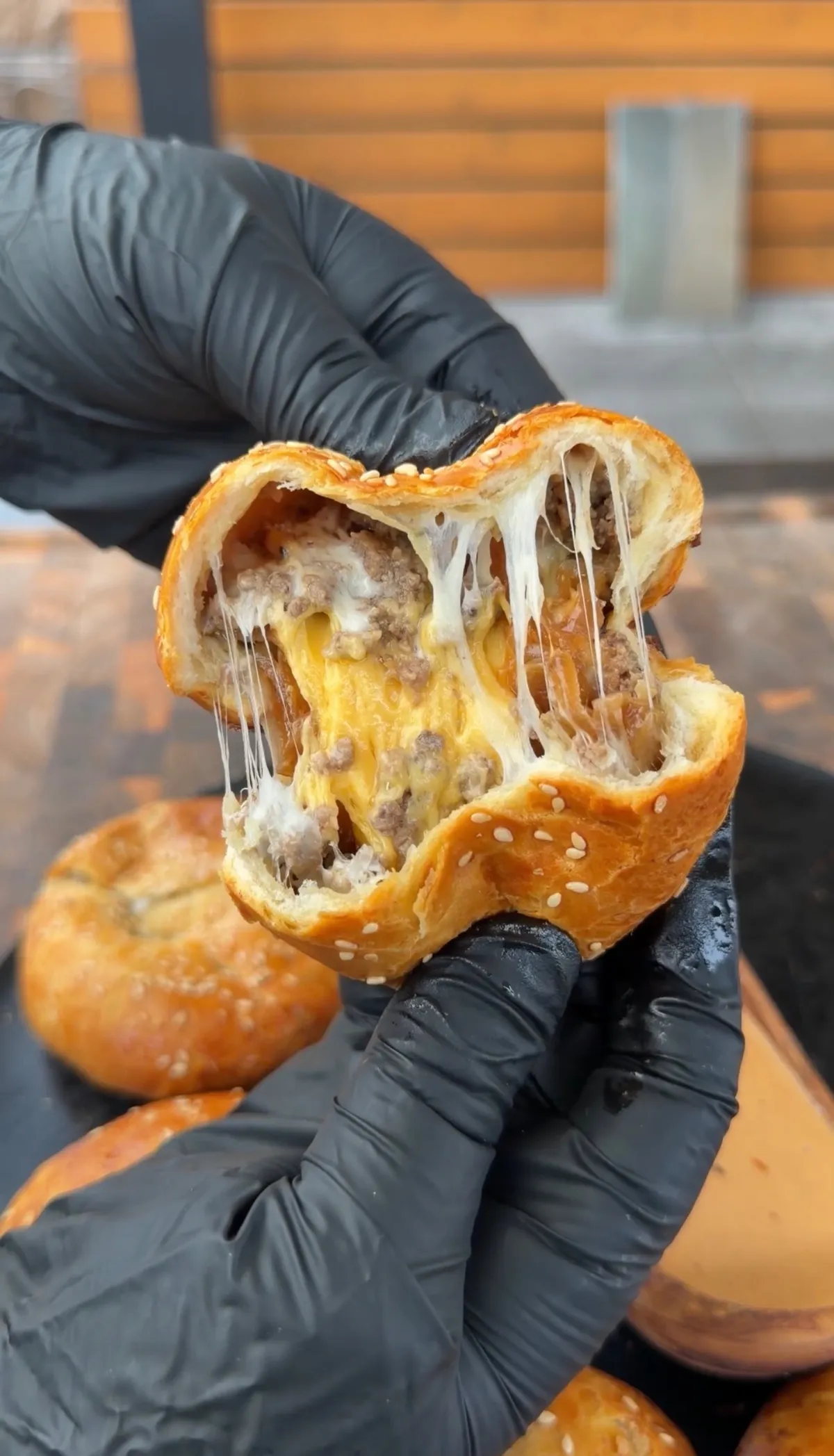Hands pulling apart a cheeseburger bomb biscuit revealing melted cheese and seasoned ground beef filling
