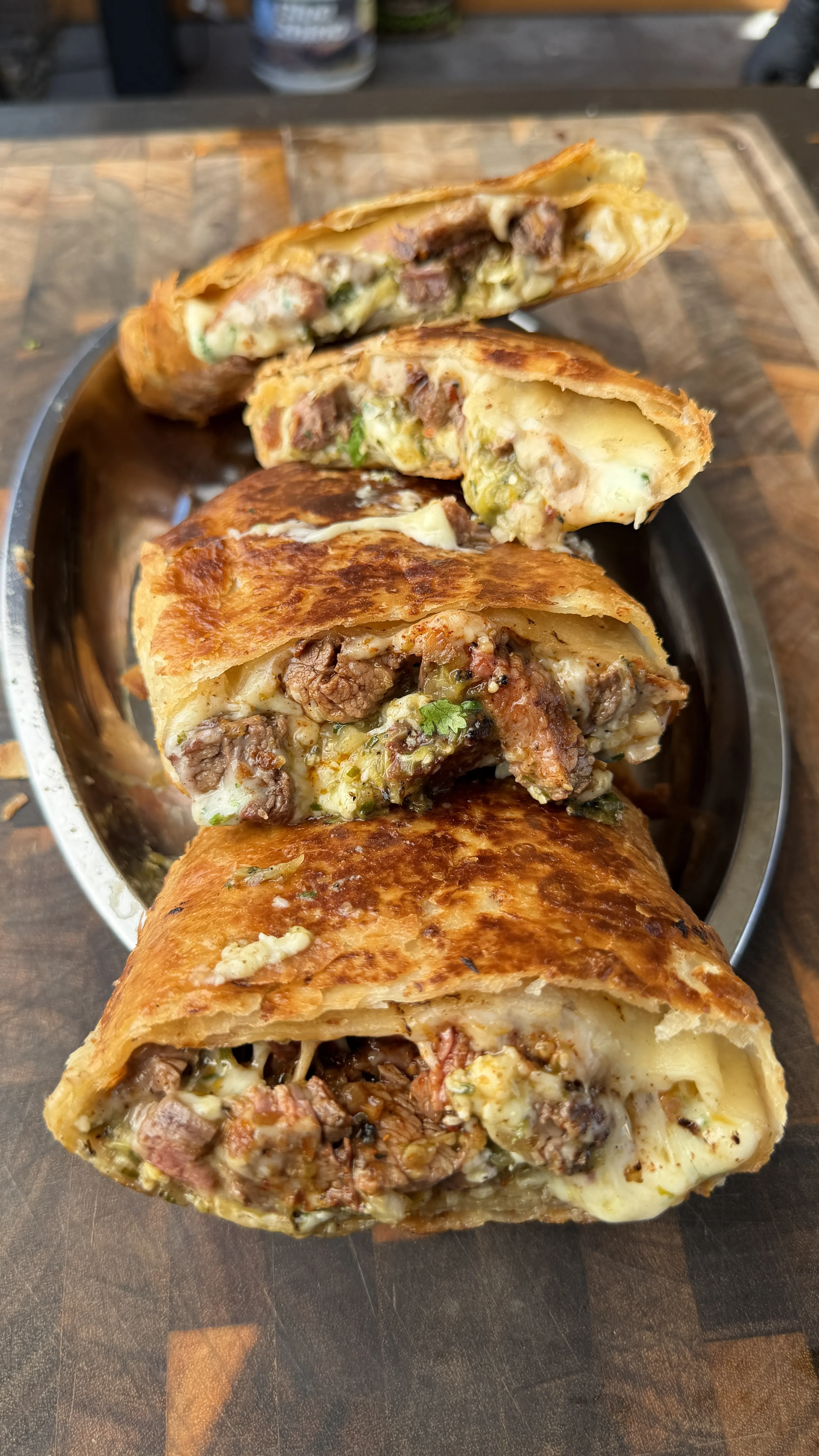 Crispy golden chimichangas cut in half revealing juicy carne asada and melted cheese filling on a metal plate