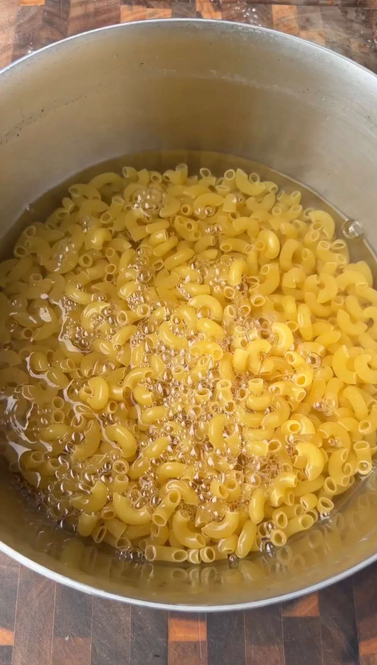 Elbow macaroni cooking al dente in a large pot of boiling salted water for creamy baked mac and cheese