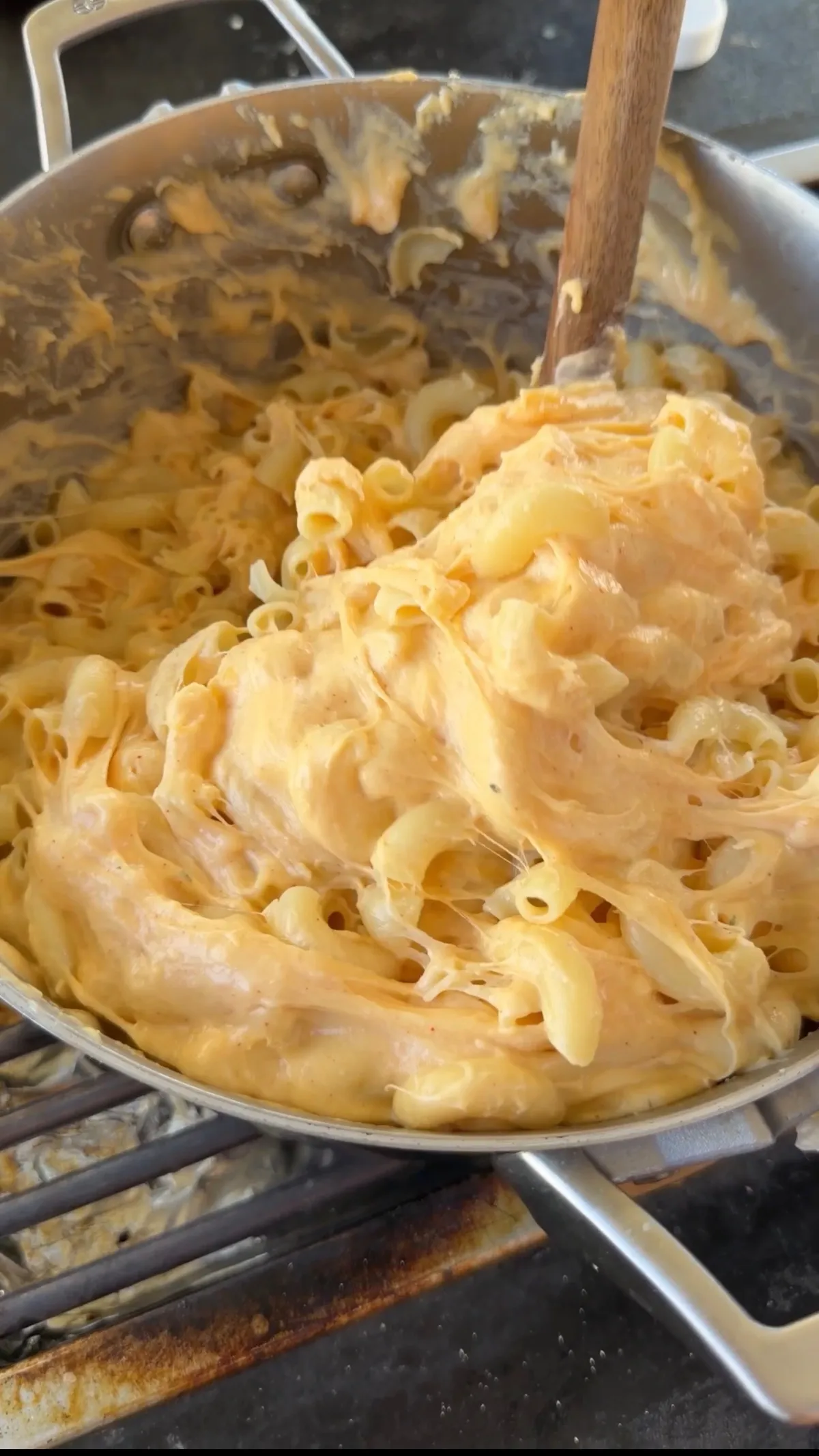 Elbow macaroni stirred into creamy mozzarella, Colby Jack, and cheddar cheese sauce in a large skillet