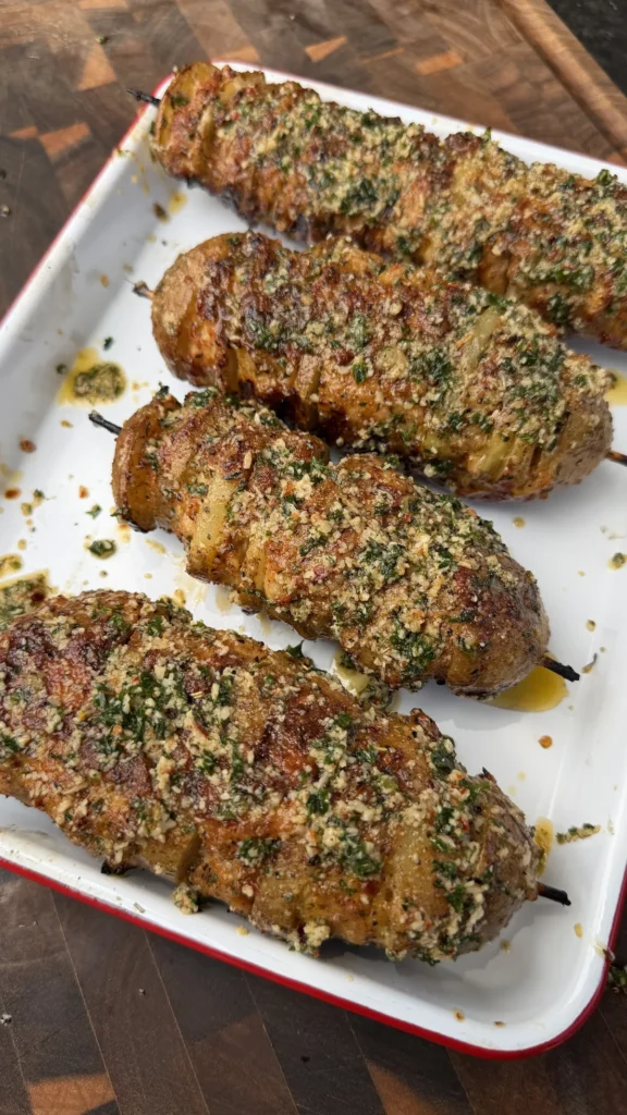 Garlic parmesan chicken and potato skewers on a white enamel tray, coated in herbs and golden breadcrumbs