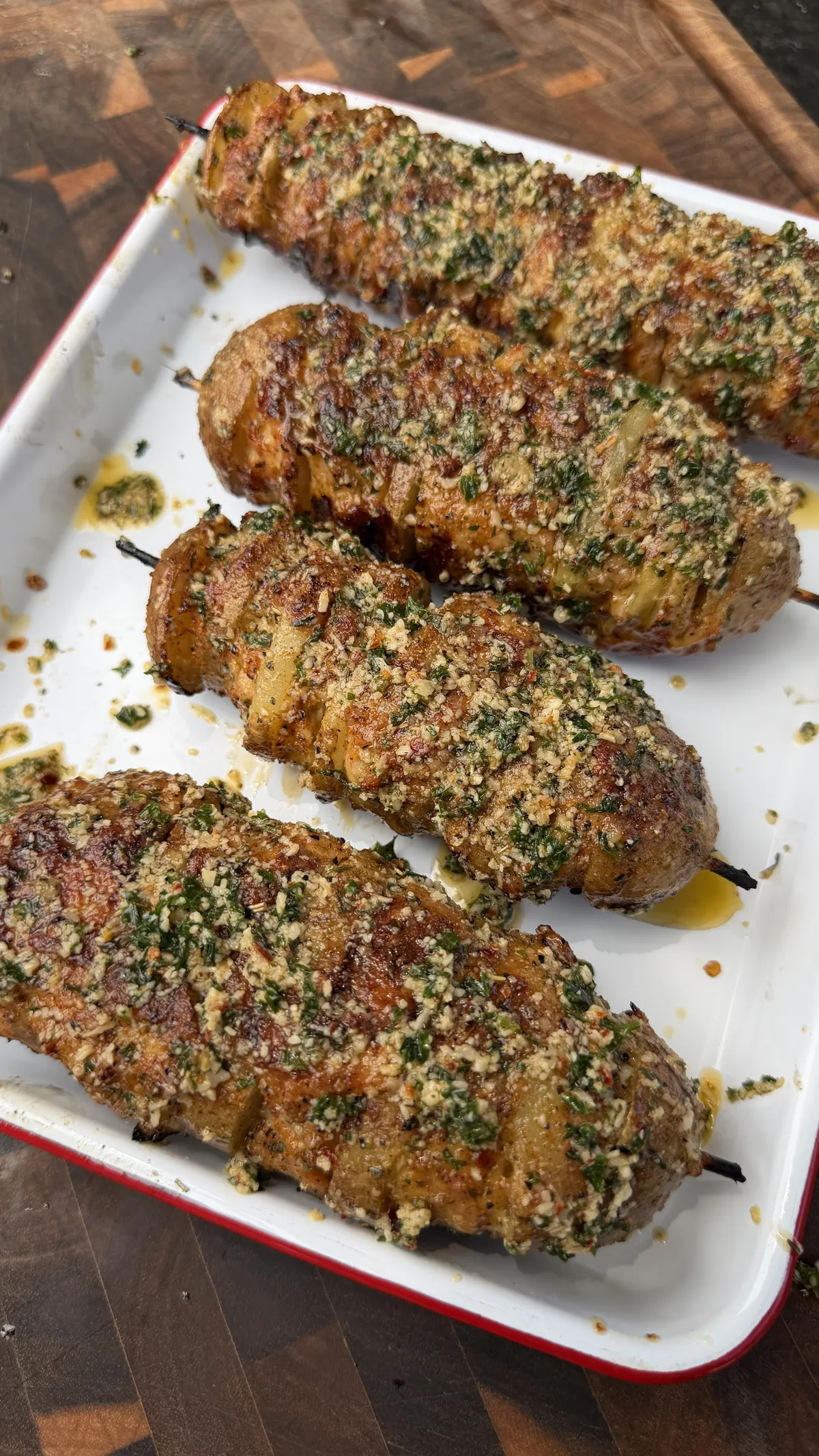 Garlic parmesan chicken and potato skewers on a white enamel tray, coated in herbs and golden breadcrumbs