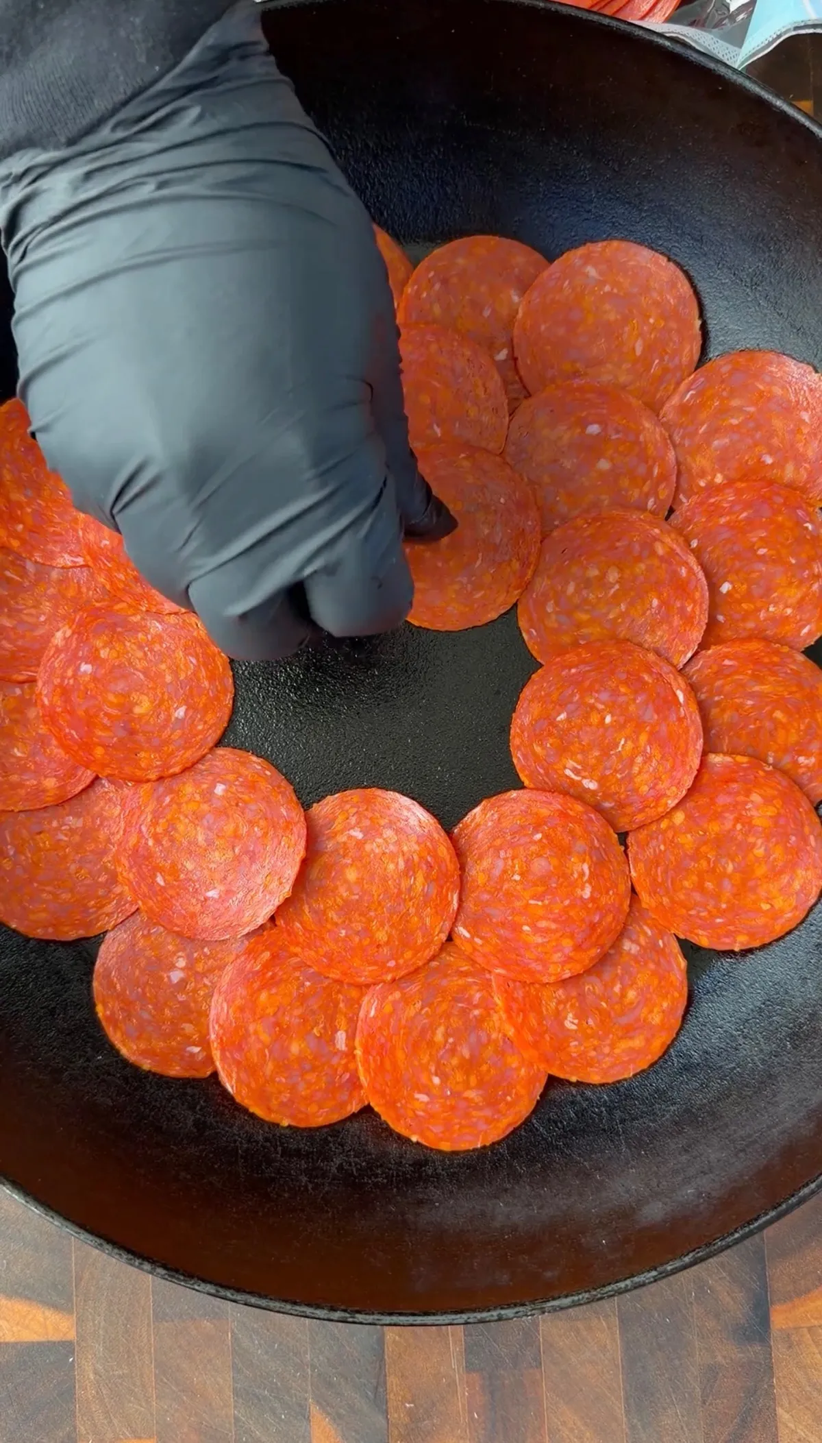 Pepperoni slices arranged in a circular ring pattern in a black cast iron skillet for upside down pizza