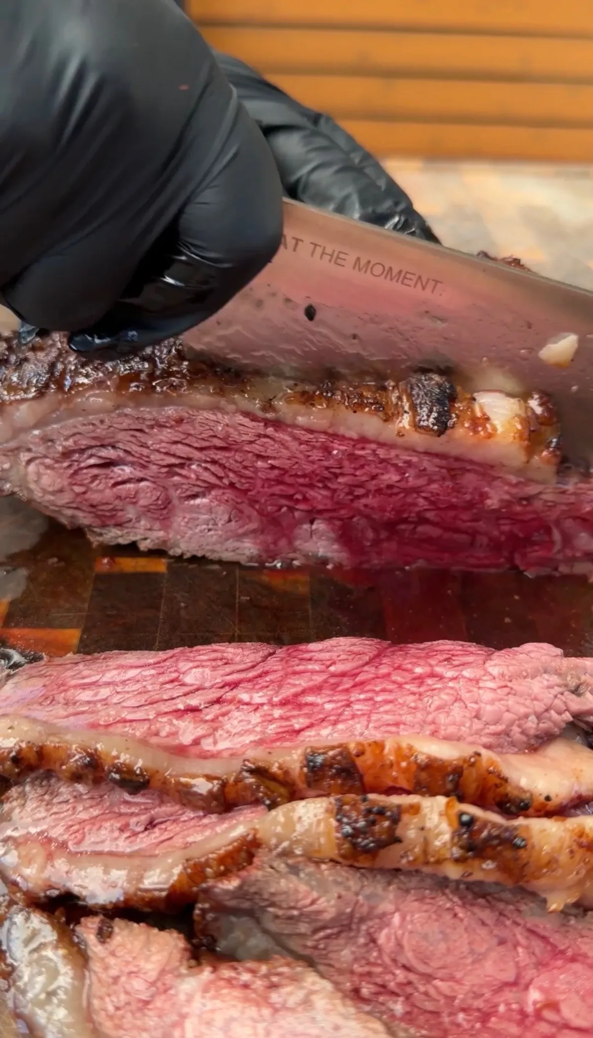Thinly sliced medium-rare picanha being cut against the grain with a knife, showing juicy pink interior and seared fat cap