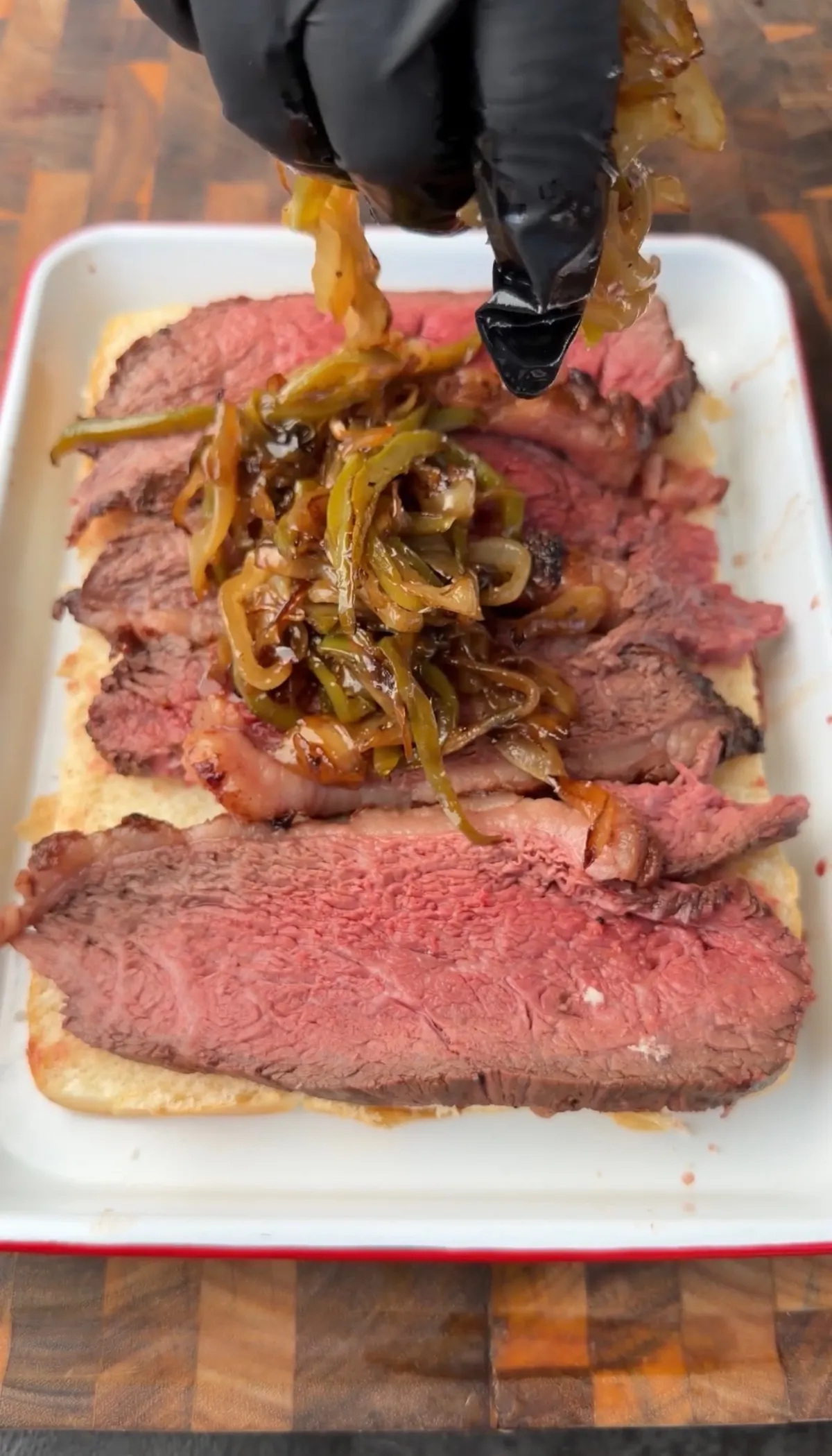 Thinly sliced picanha on Hawaiian rolls topped with sautéed green bell pepper and sweet onion in a baking dish