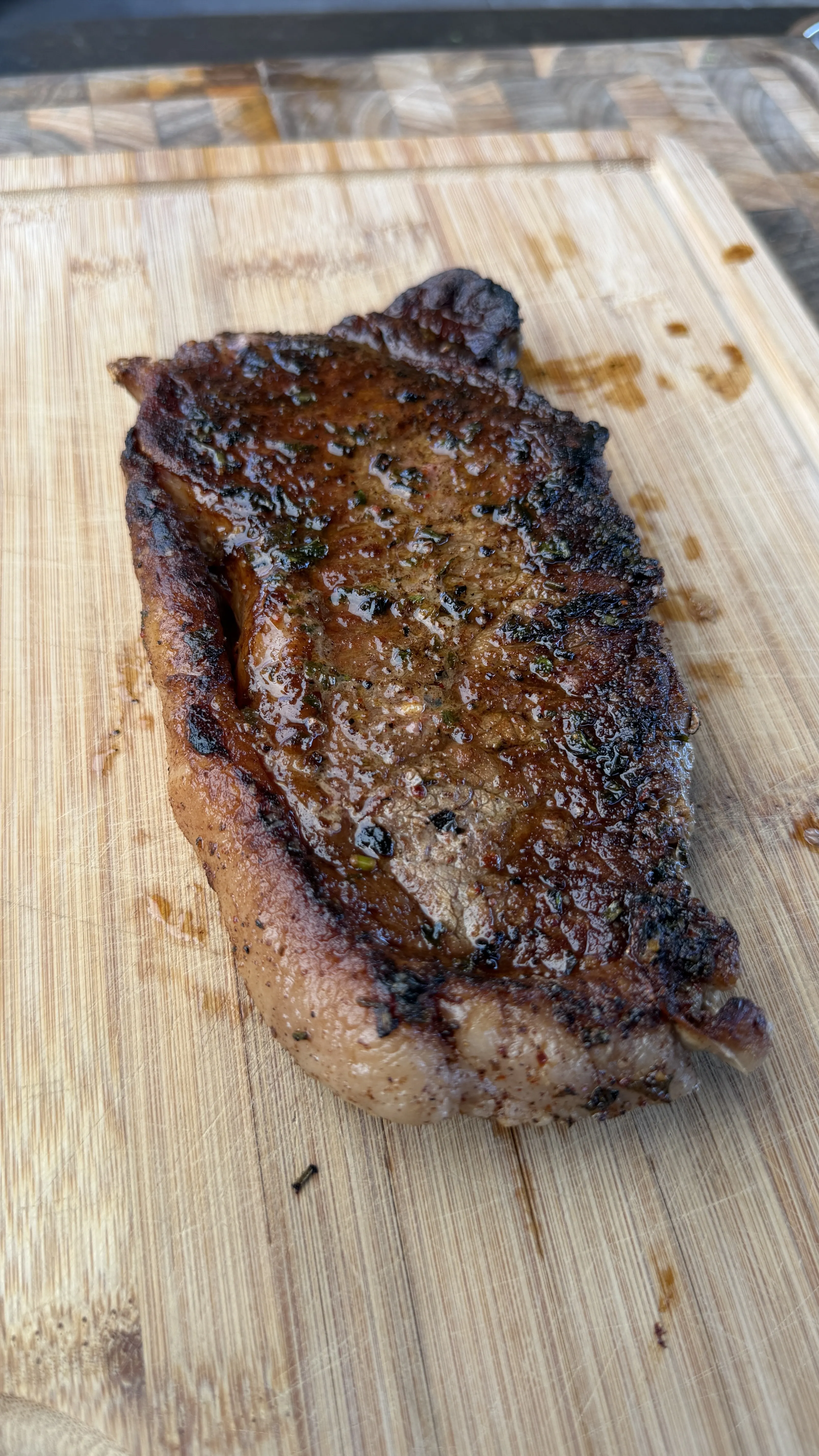 Juicy seared steak glazed with cowboy butter resting on a wooden cutting board with a caramelized crust