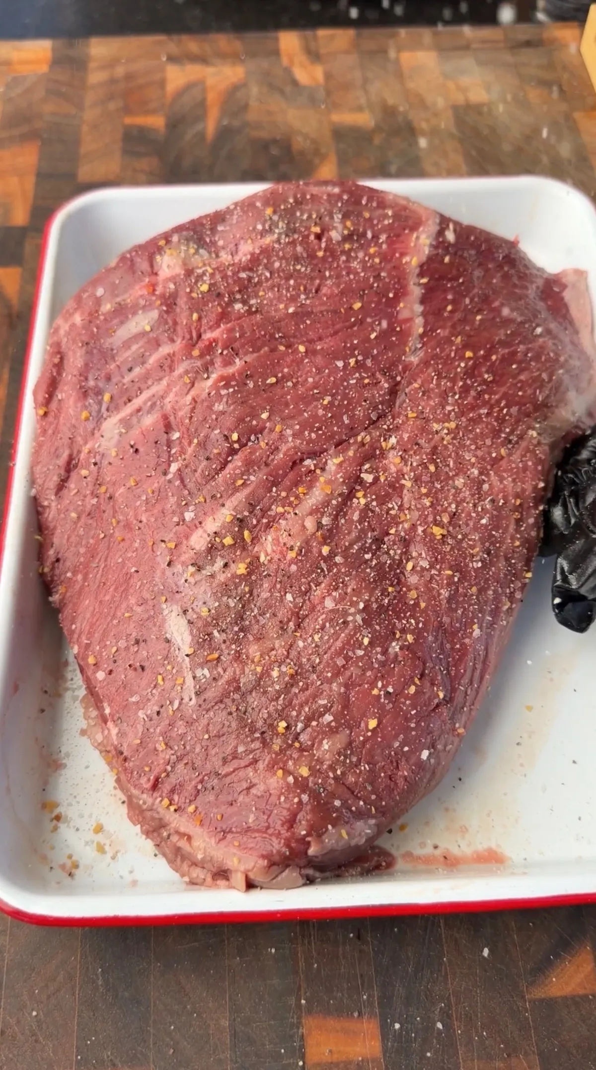 Raw picanha sirloin cap seasoned with salt, pepper, and garlic in a white baking dish, ready to sear