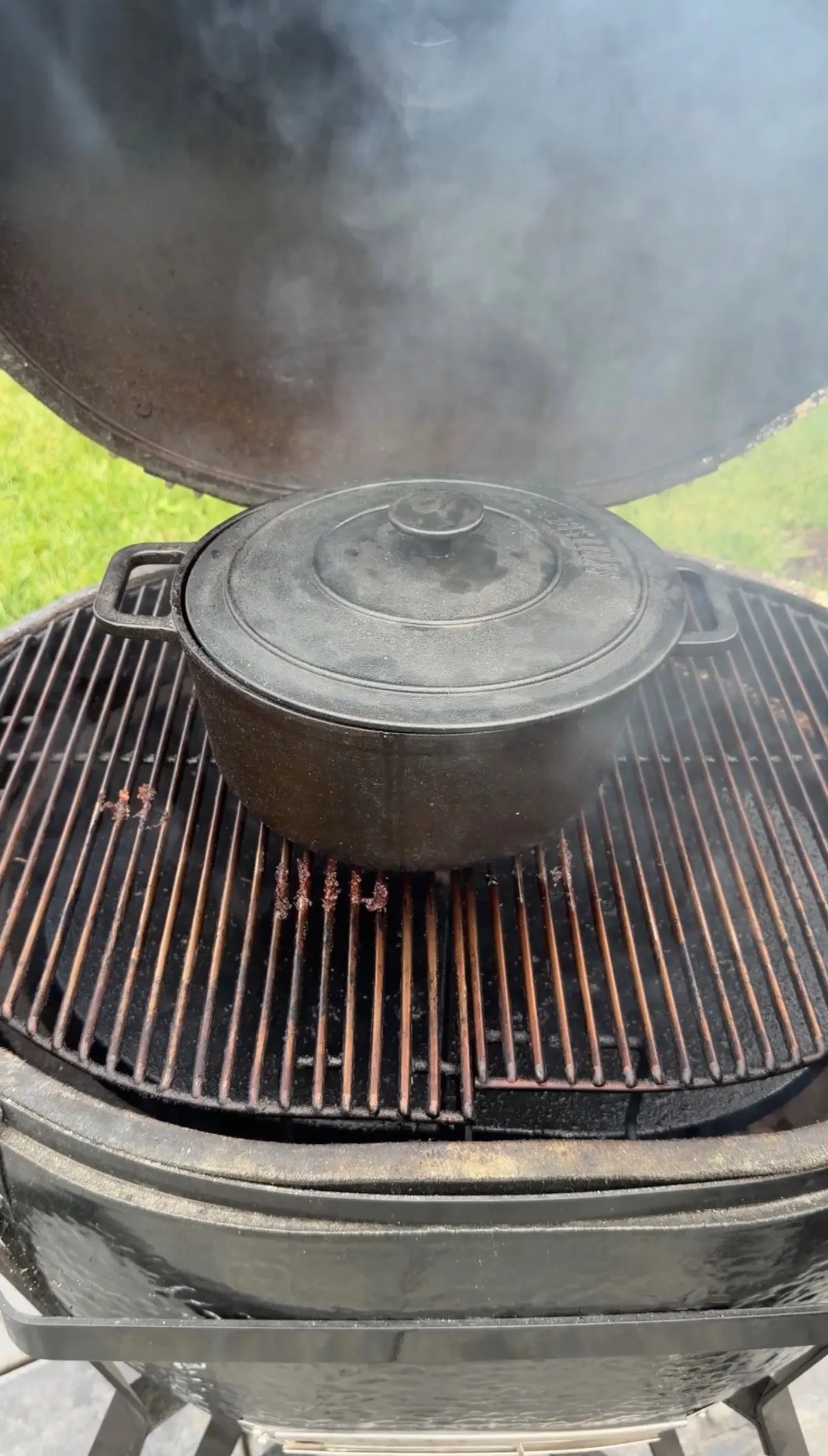 Cast iron Dutch oven with lid on smoker grill at 250°F during brown sugar bourbon braise step
