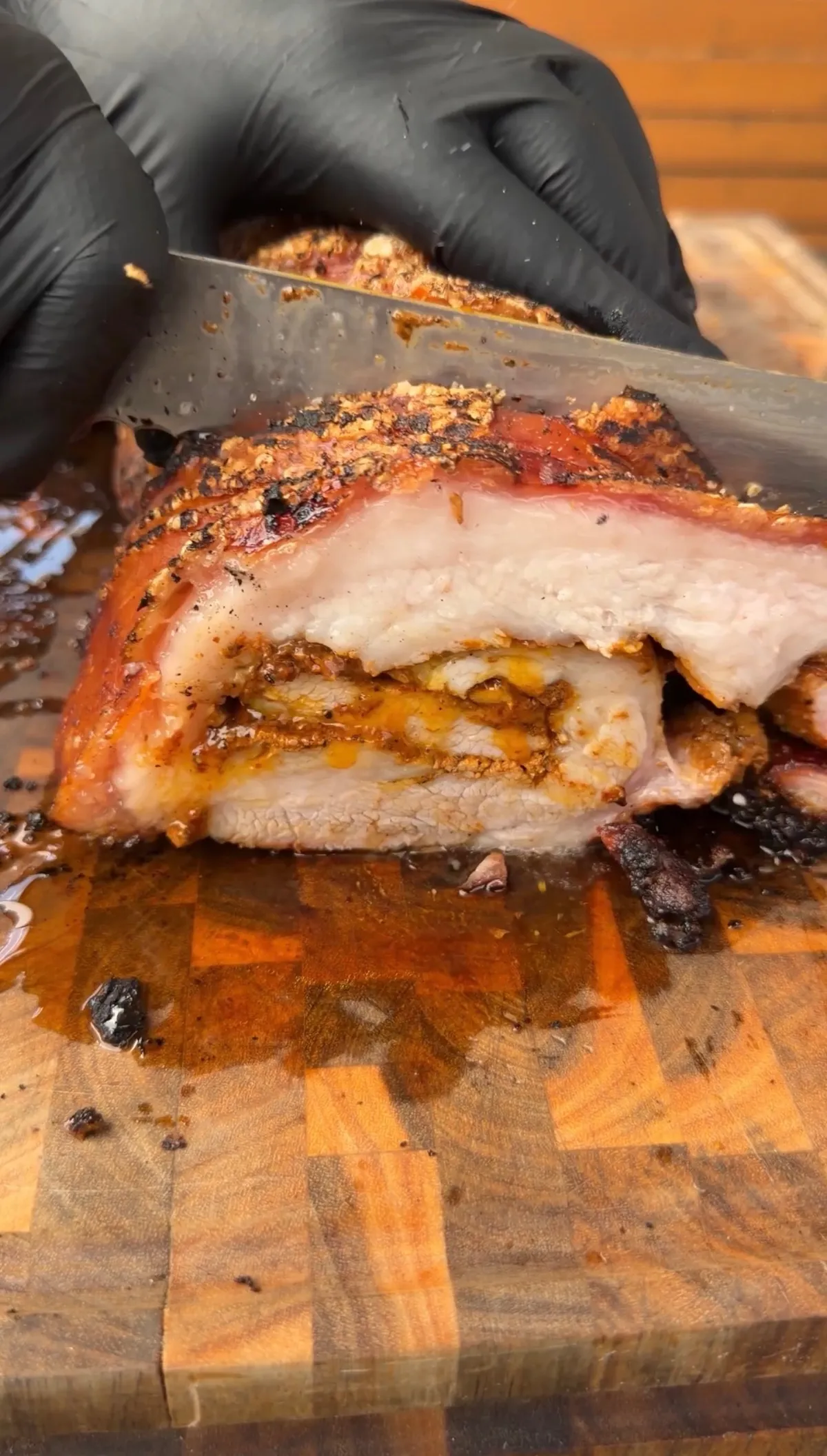 Sliced smoked pork belly porchetta with spice crust and juicy layers on a wooden cutting board