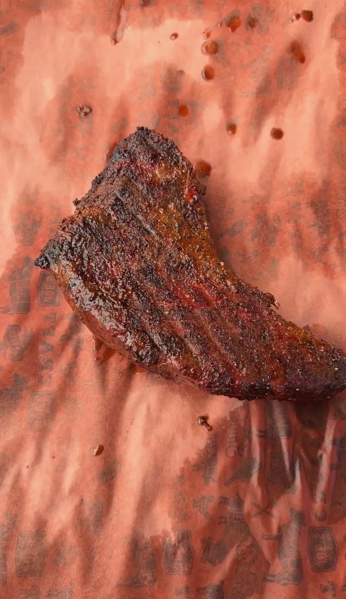 Tri-tip cooked brisket-style with dark smoky bark crust resting on pink butcher paper