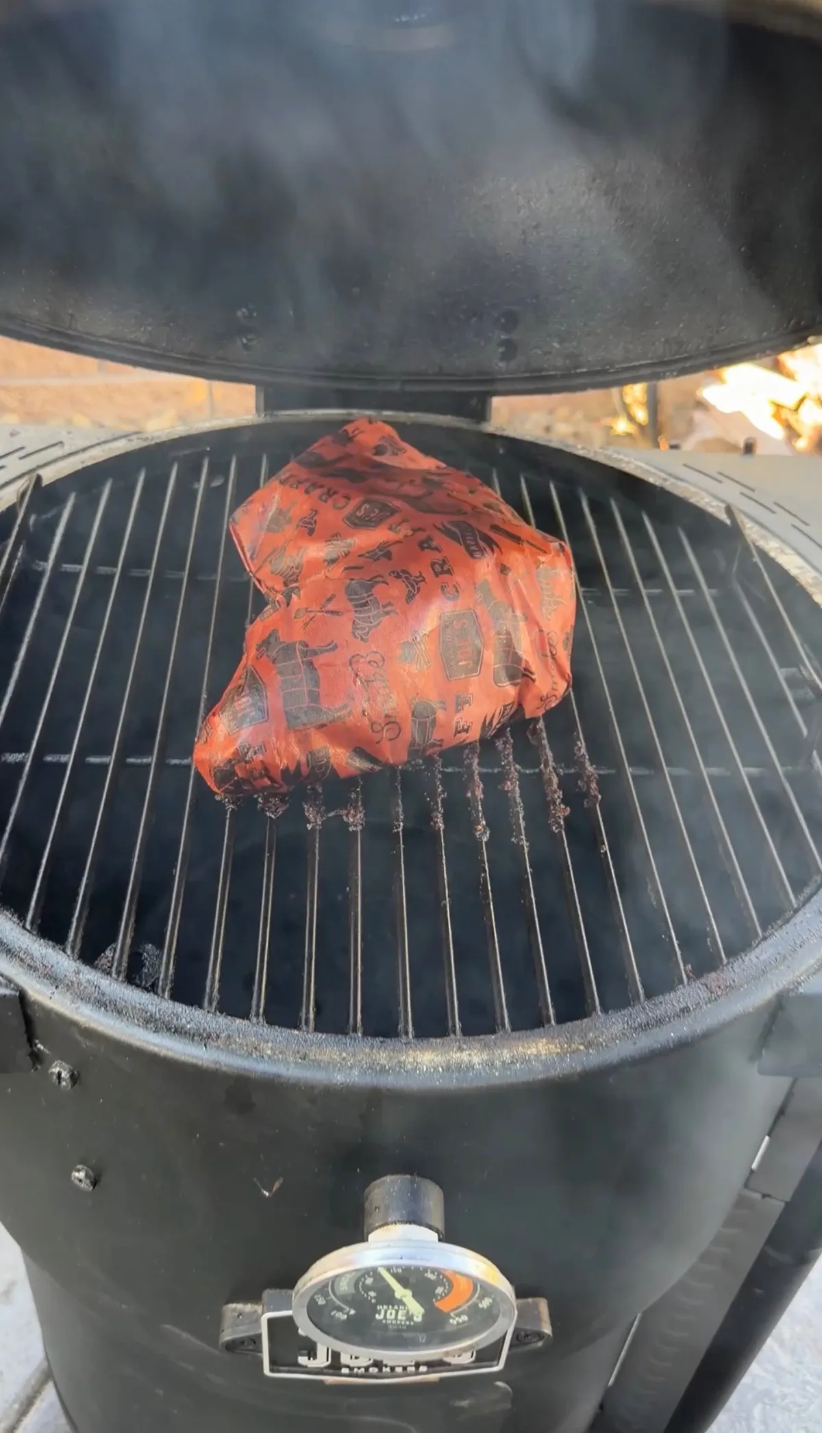 Tri-tip brisket wrapped in branded butcher paper smoking on an Oklahoma Joe's charcoal smoker