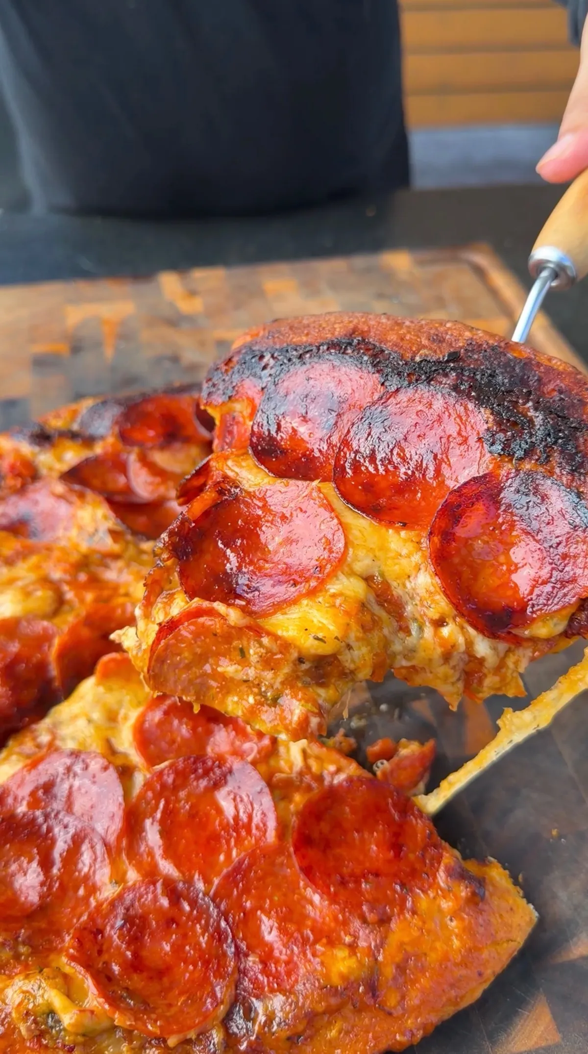 A cheesy upside down pepperoni pizza slice being lifted, showing crispy caramelized pepperoni and melted cheese