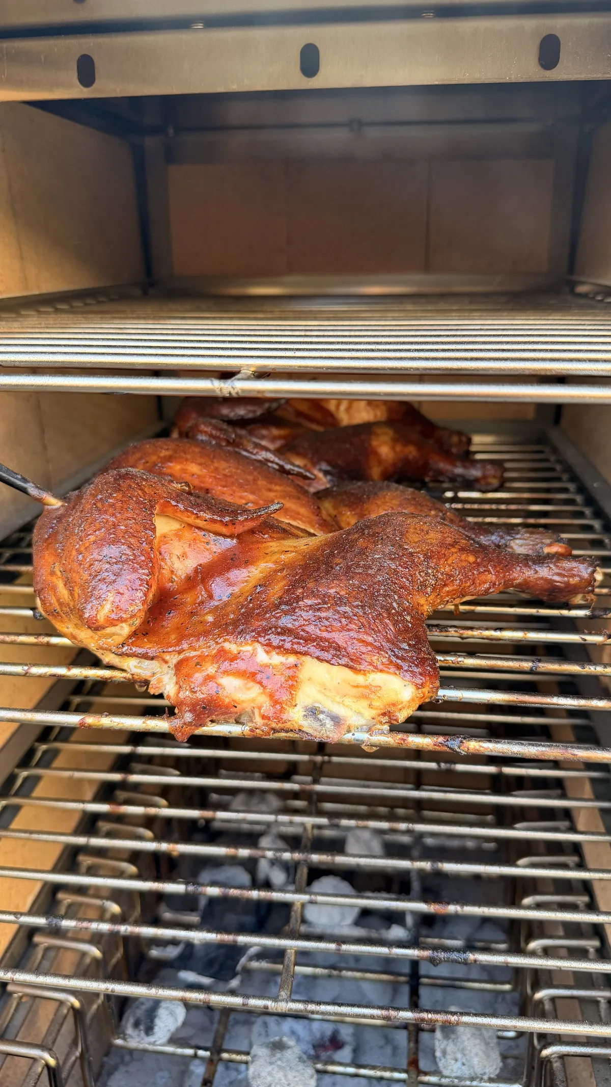 Two spatchcock chickens with sticky BBQ glaze smoking on applewood smoker grates at 300–350°F