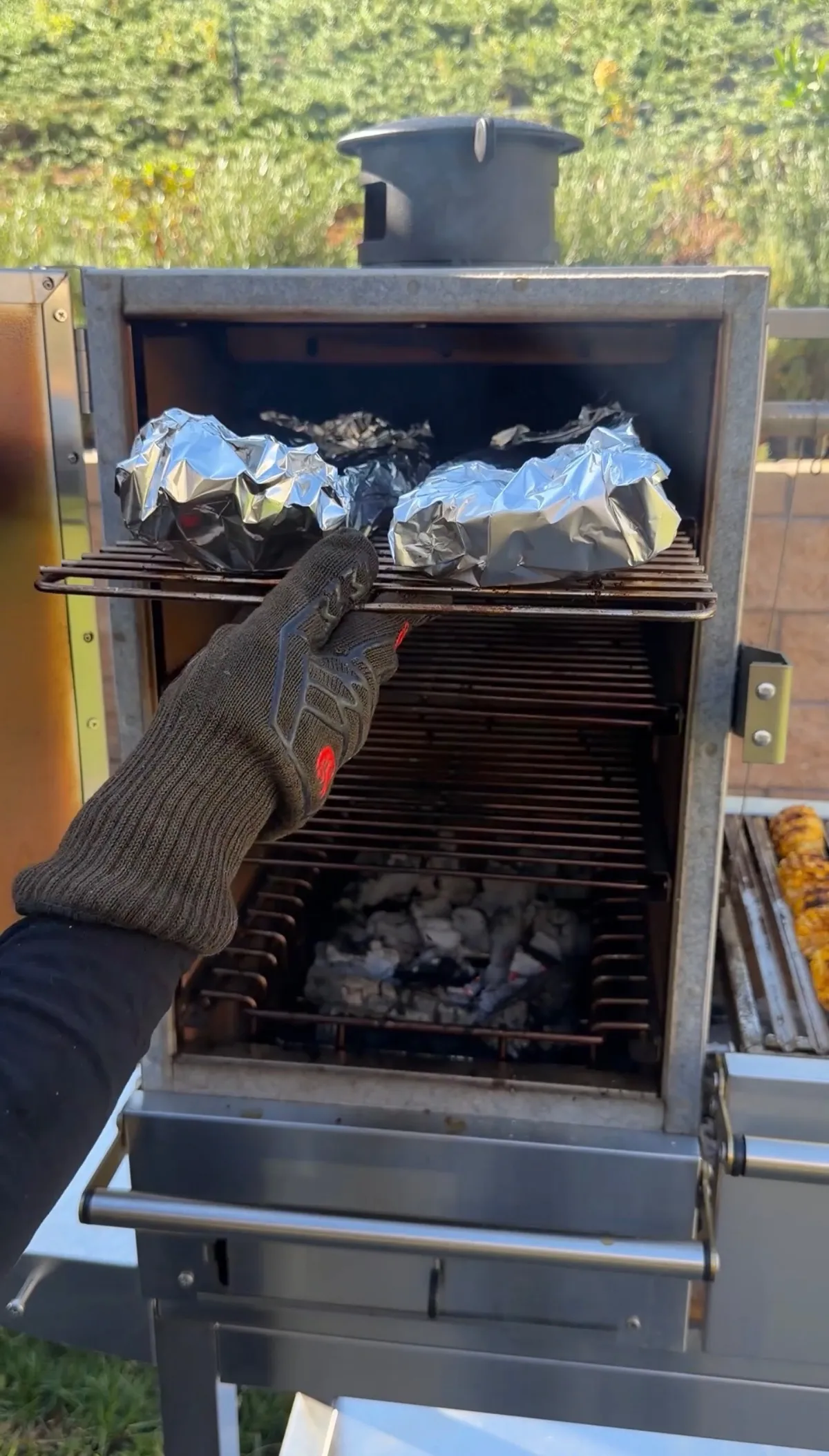 Baby back ribs wrapped in foil with butter, brown sugar, and apple juice on smoker grate at 275–300°F