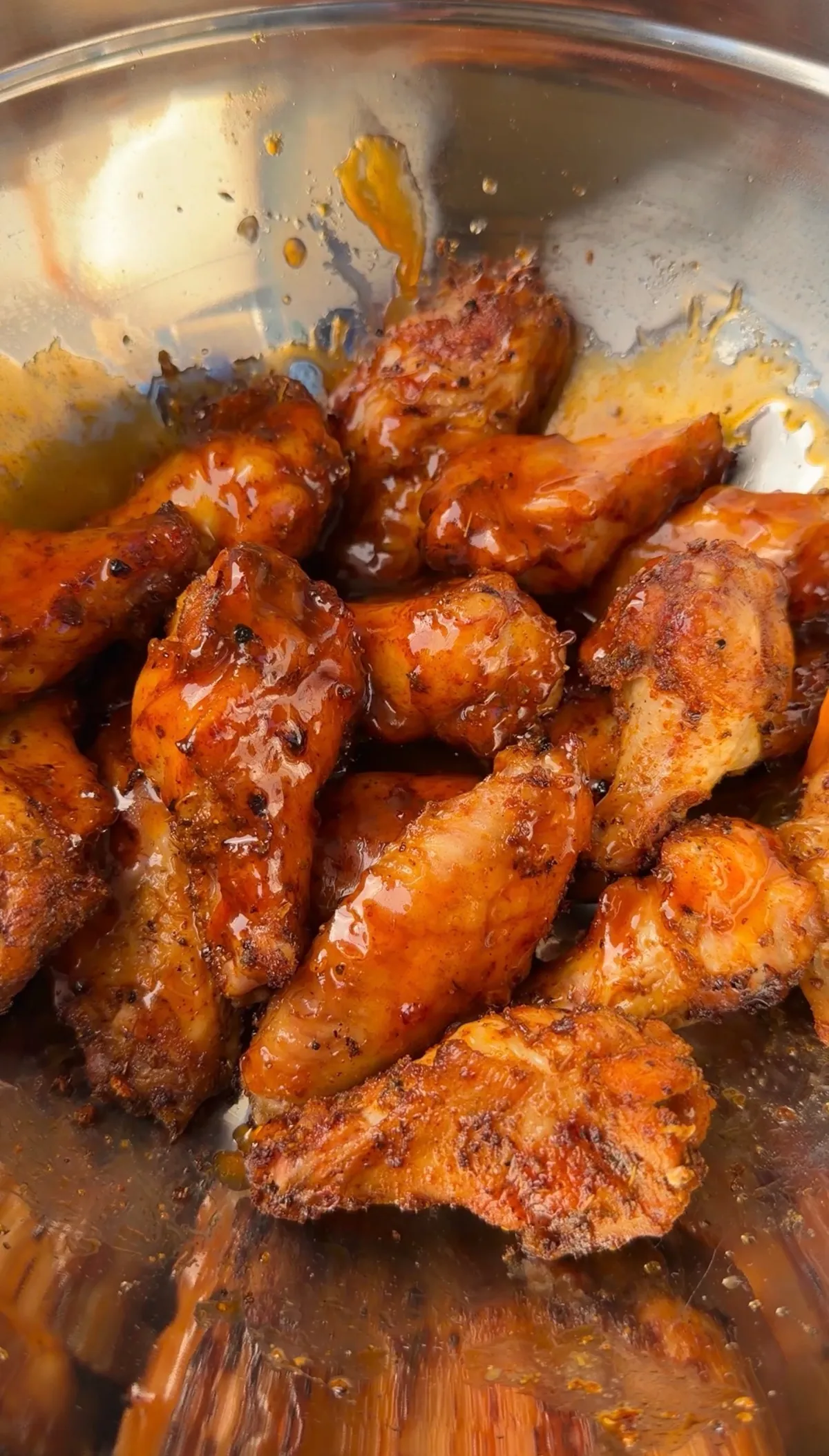Crispy grilled Cajun wings tossed in jalapeño honey butter sauce, glistening in a stainless steel mixing bowl
