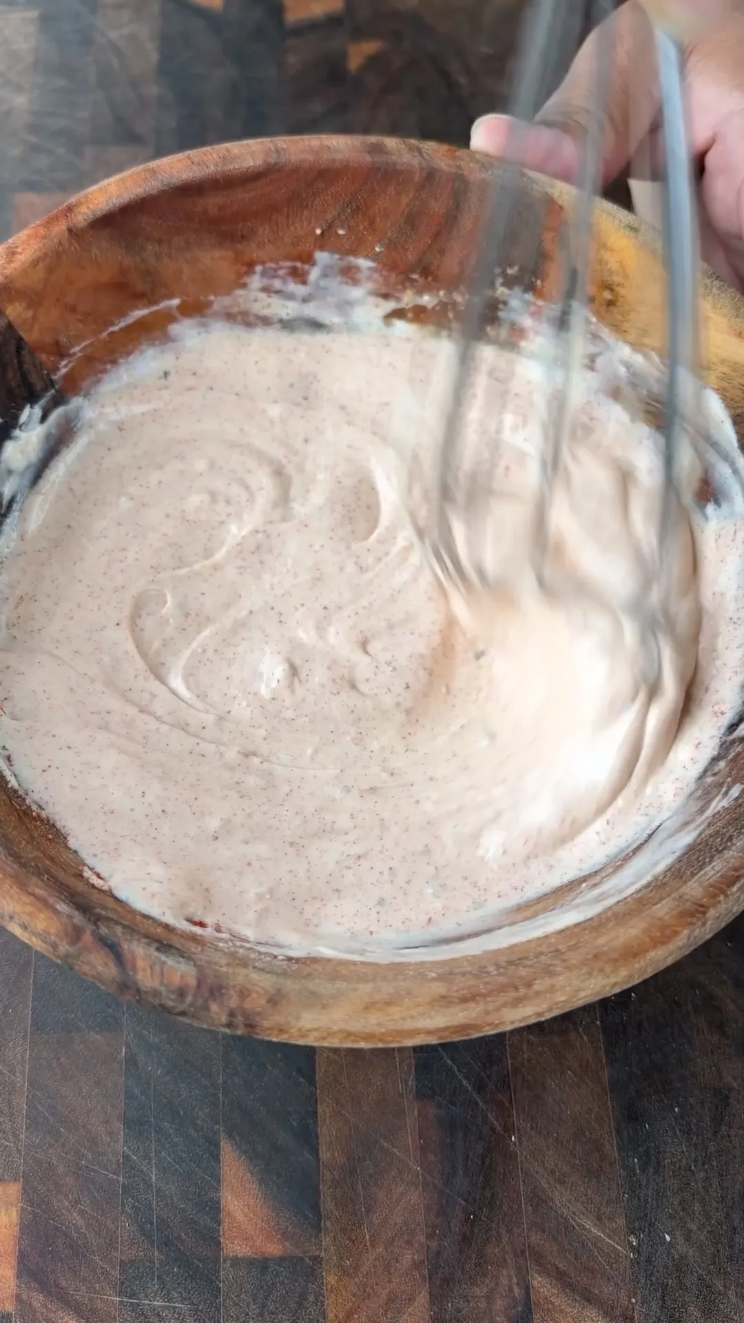Chipotle mayo with smoked paprika and garlic paste being whisked smooth in a wooden bowl