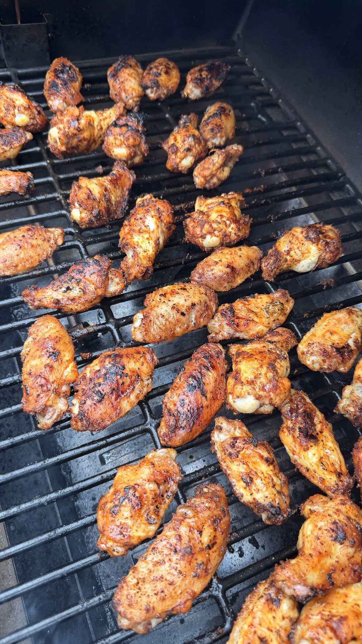 4 lbs of chipotle-seasoned chicken wings cooking on a smoker at 350°F until golden and crispy