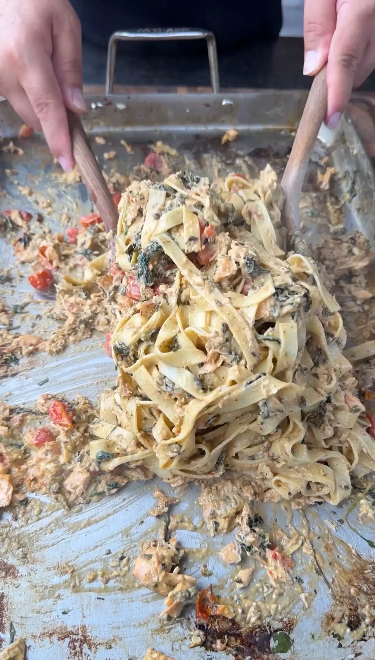 Fettuccine tossed with creamy pesto salmon sauce, wilted spinach, and cherry tomatoes in a baking pan