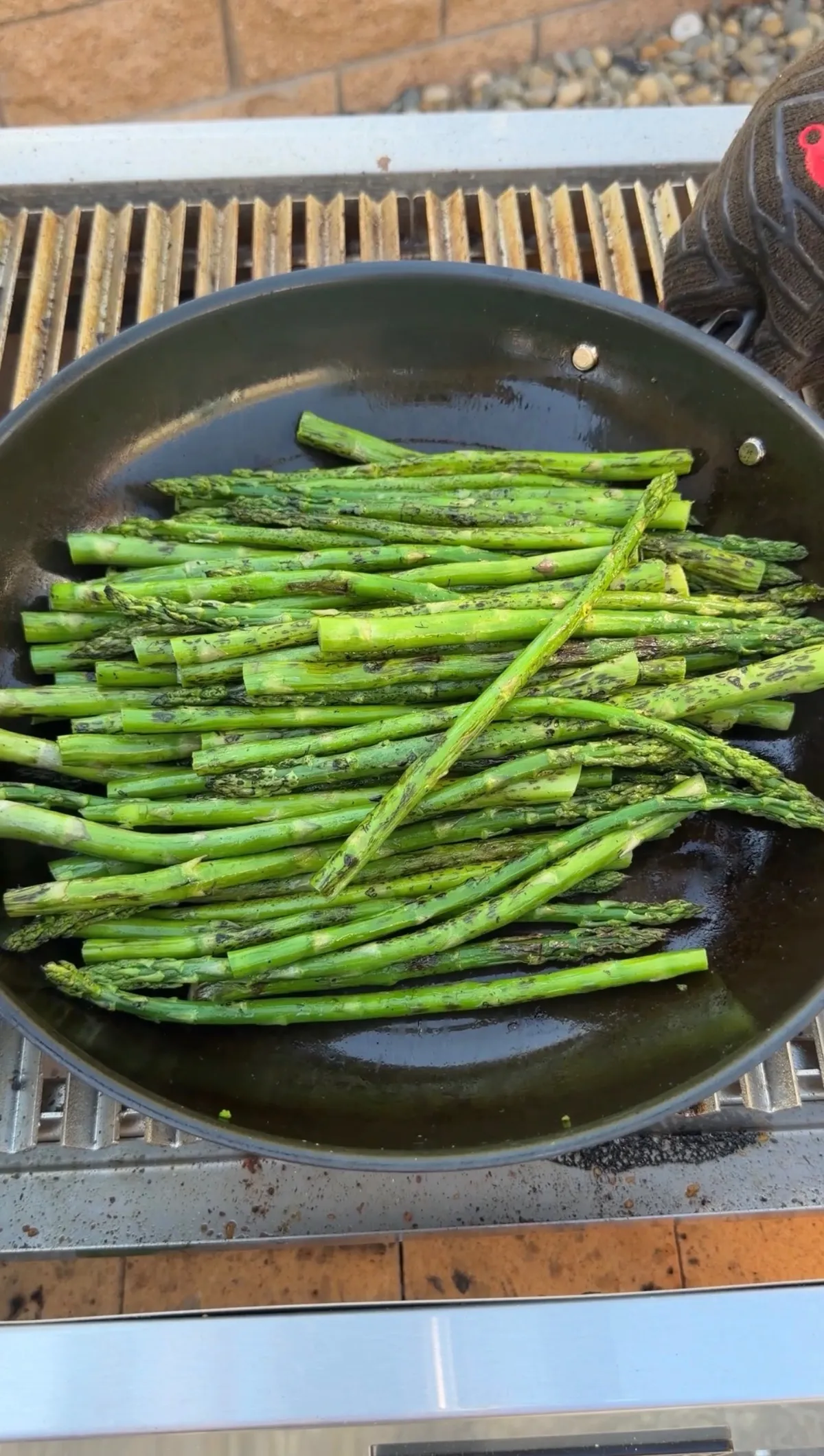 Crispy asparagus seasoned with salt, pepper, and garlic powder cooking in a skillet on the grill