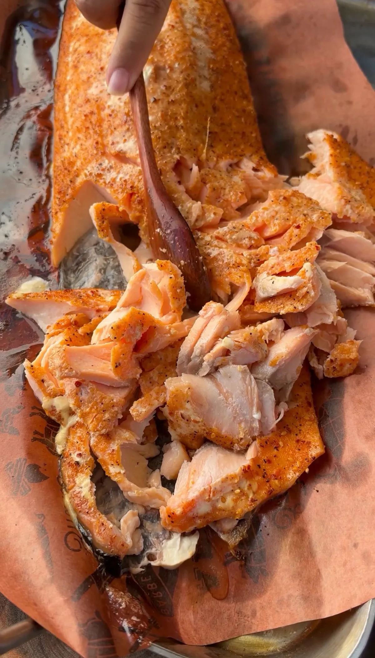 Hand flaking smoked salmon seasoned with seafood seasoning into tender pieces on butcher paper