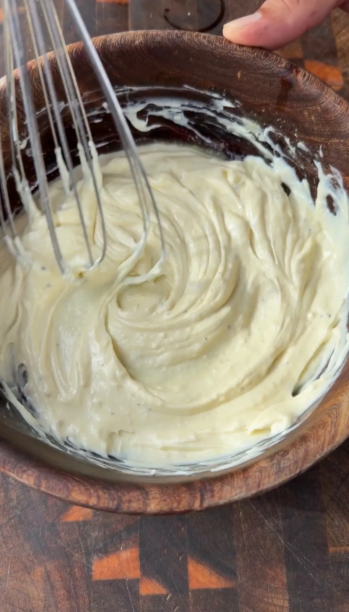 Creamy garlic aioli being whisked in a wooden bowl, combining mayonnaise, minced garlic, lemon juice, and Dijon mustard