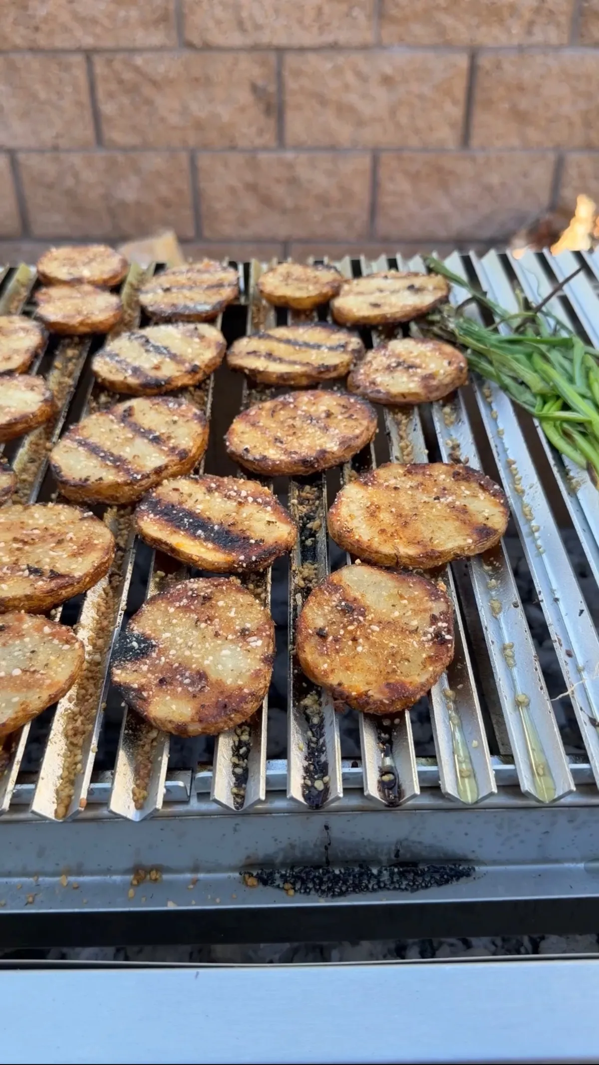 Grilled Cajun Parmesan russet potato slices with crispy browned edges cooking on outdoor BBQ grill grates