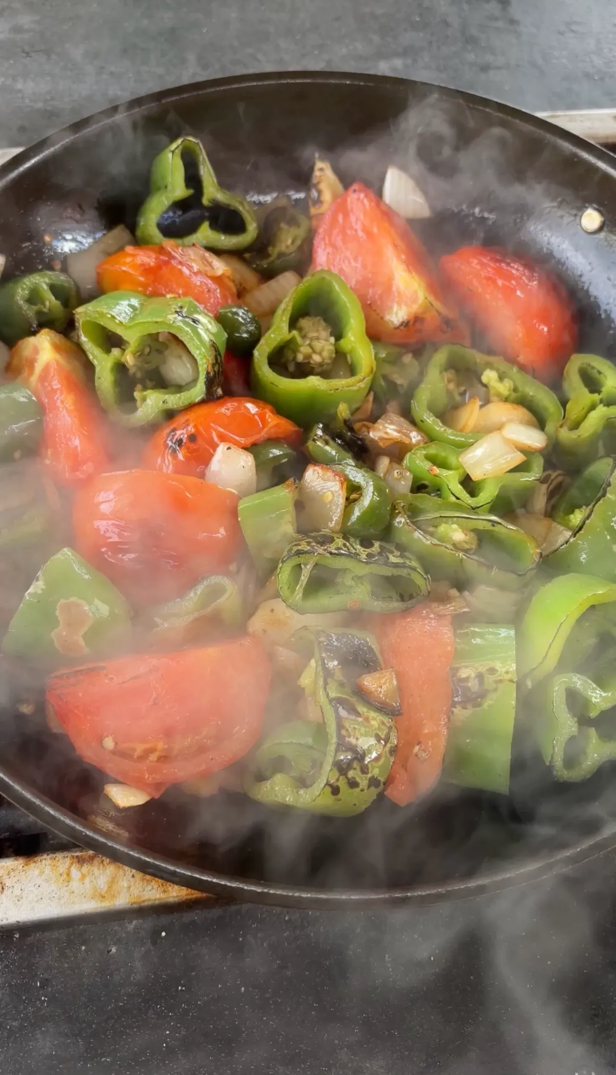 Hatch green chiles, Roma tomatoes, white onion, and jalapeño charring in a hot skillet for roasted Hatch chile salsa