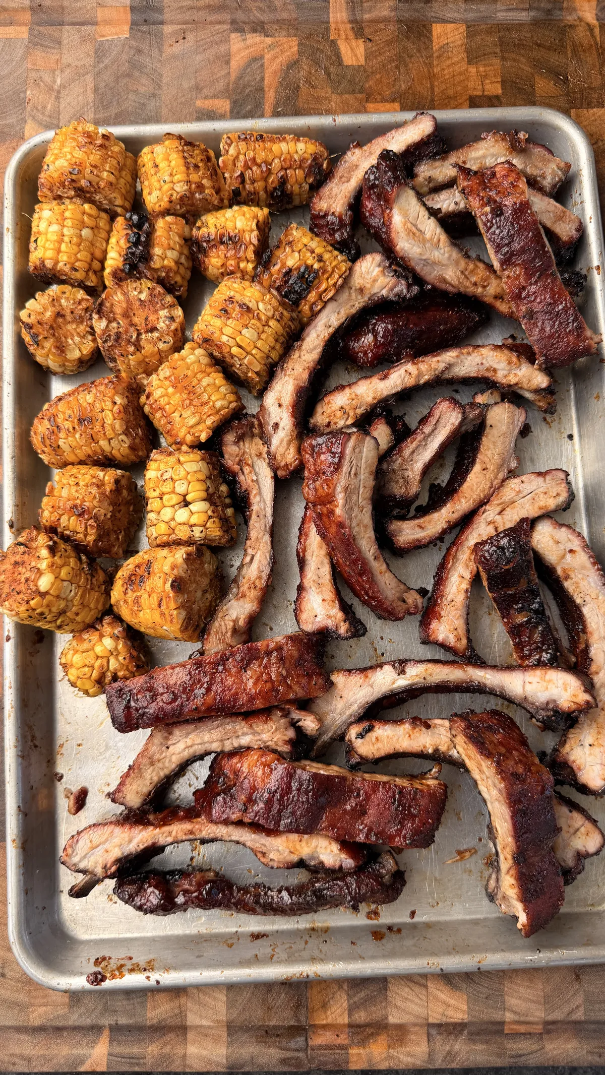 Sliced honey chipotle baby back ribs with sticky BBQ glaze and roasted chipotle corn on a sheet pan