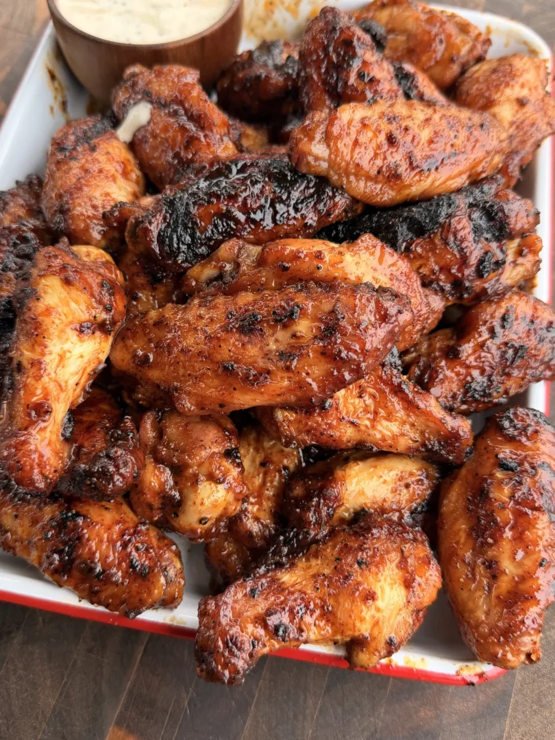 Honey chipotle smoked chicken wings tossed in glaze piled on a tray with a side of ranch dressing
