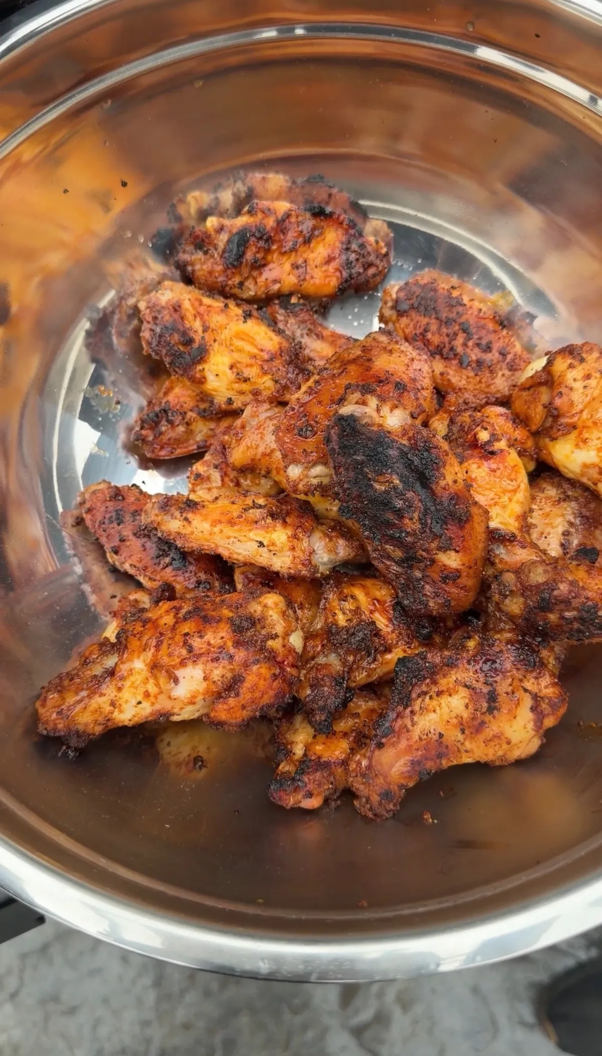 Honey chipotle smoked chicken wings tossed in glaze in a stainless steel mixing bowl