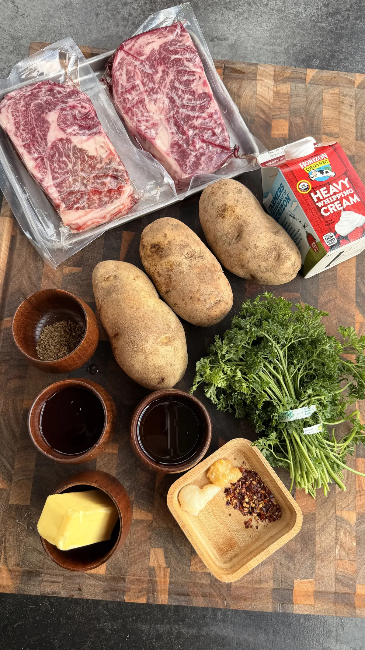 Ingredients for steak bites with mashed potatoes and chimichurri: ribeye steaks, russet potatoes, heavy cream, butter, parsley, red pepper flakes, and red wine vinegar