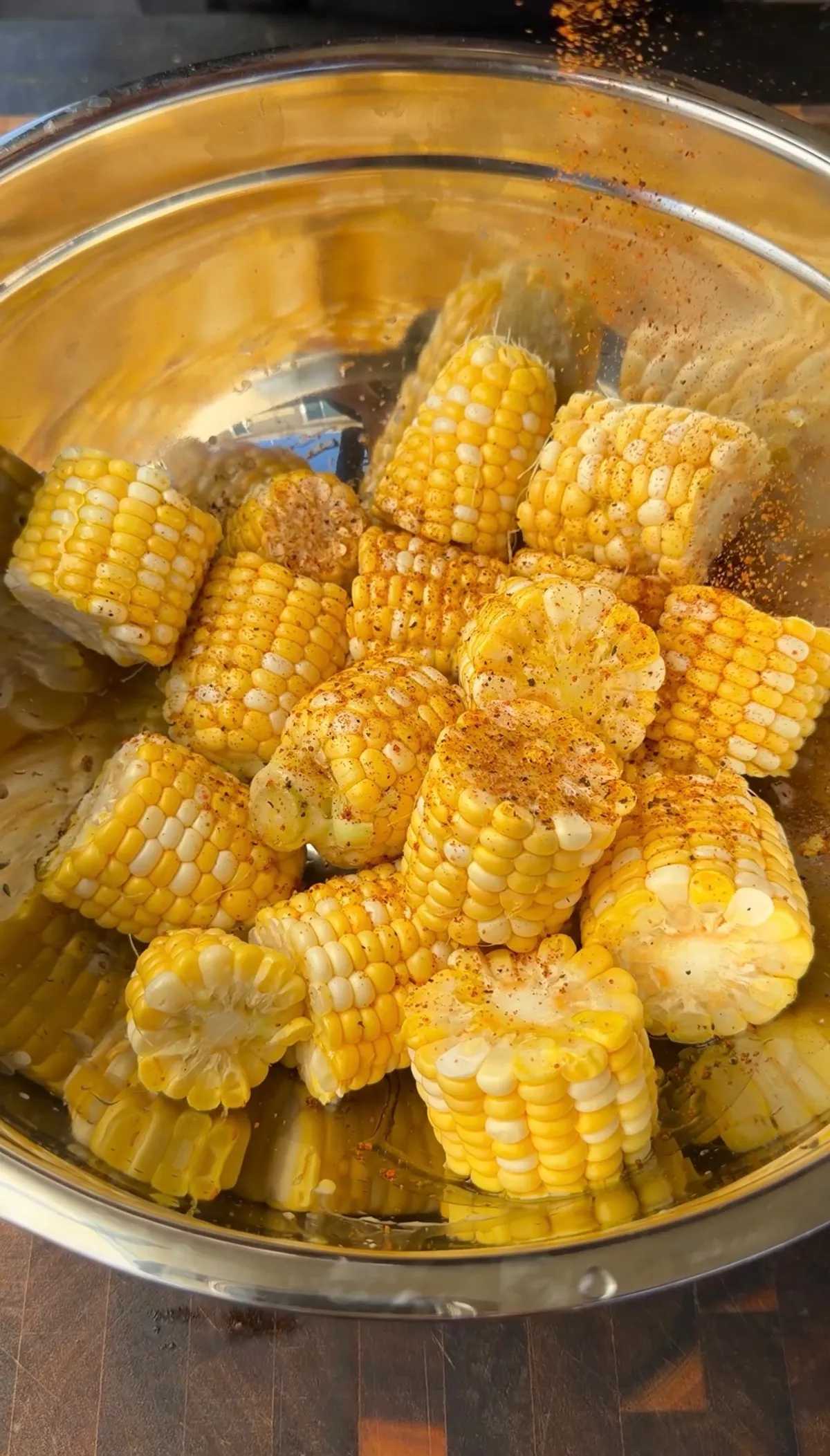 Cut corn on the cob pieces tossed with olive oil and chipotle BBQ rub in a stainless steel mixing bowl