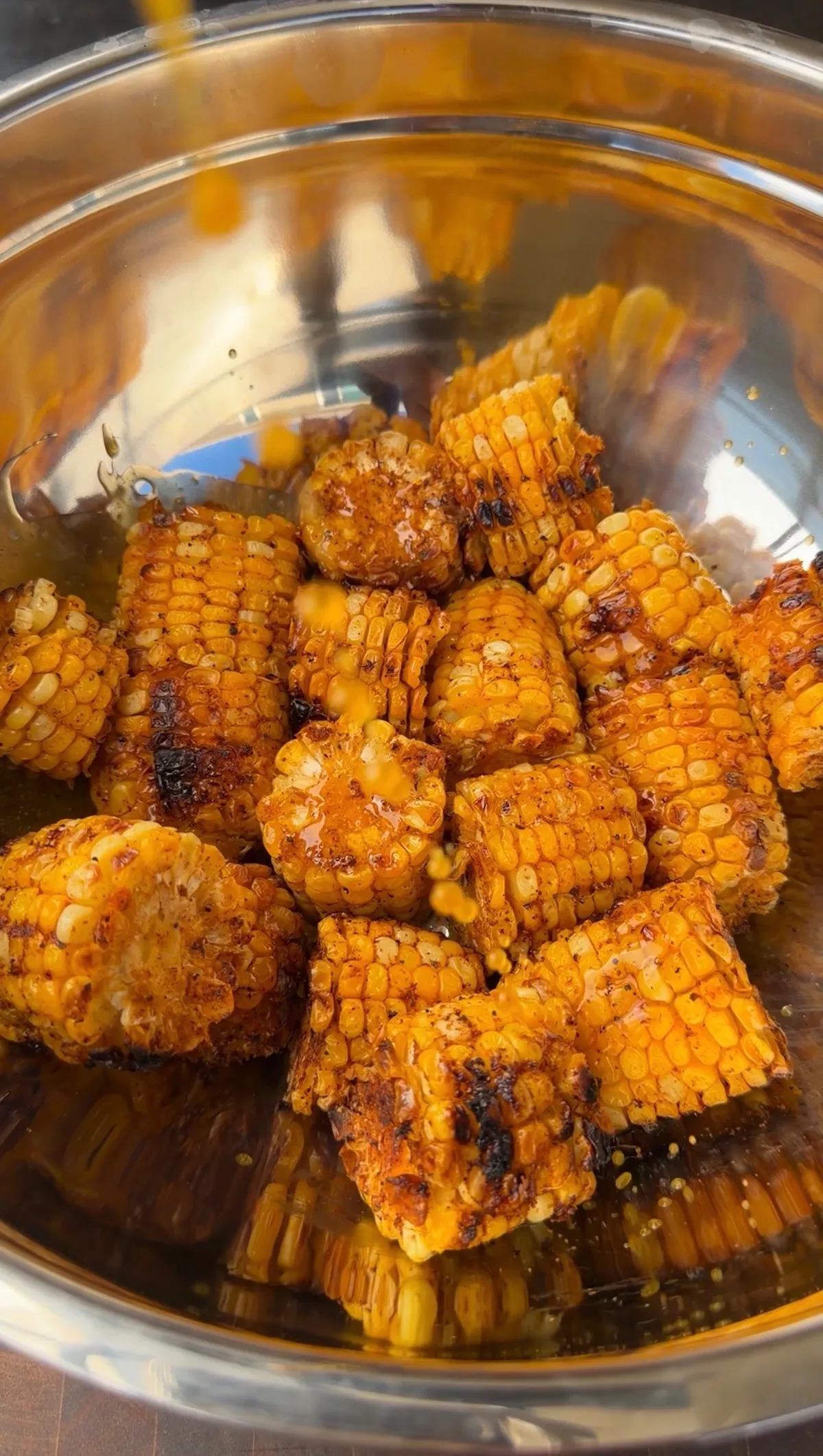 Roasted chipotle corn cut into thirds, charred and tossed with butter in a stainless steel mixing bowl