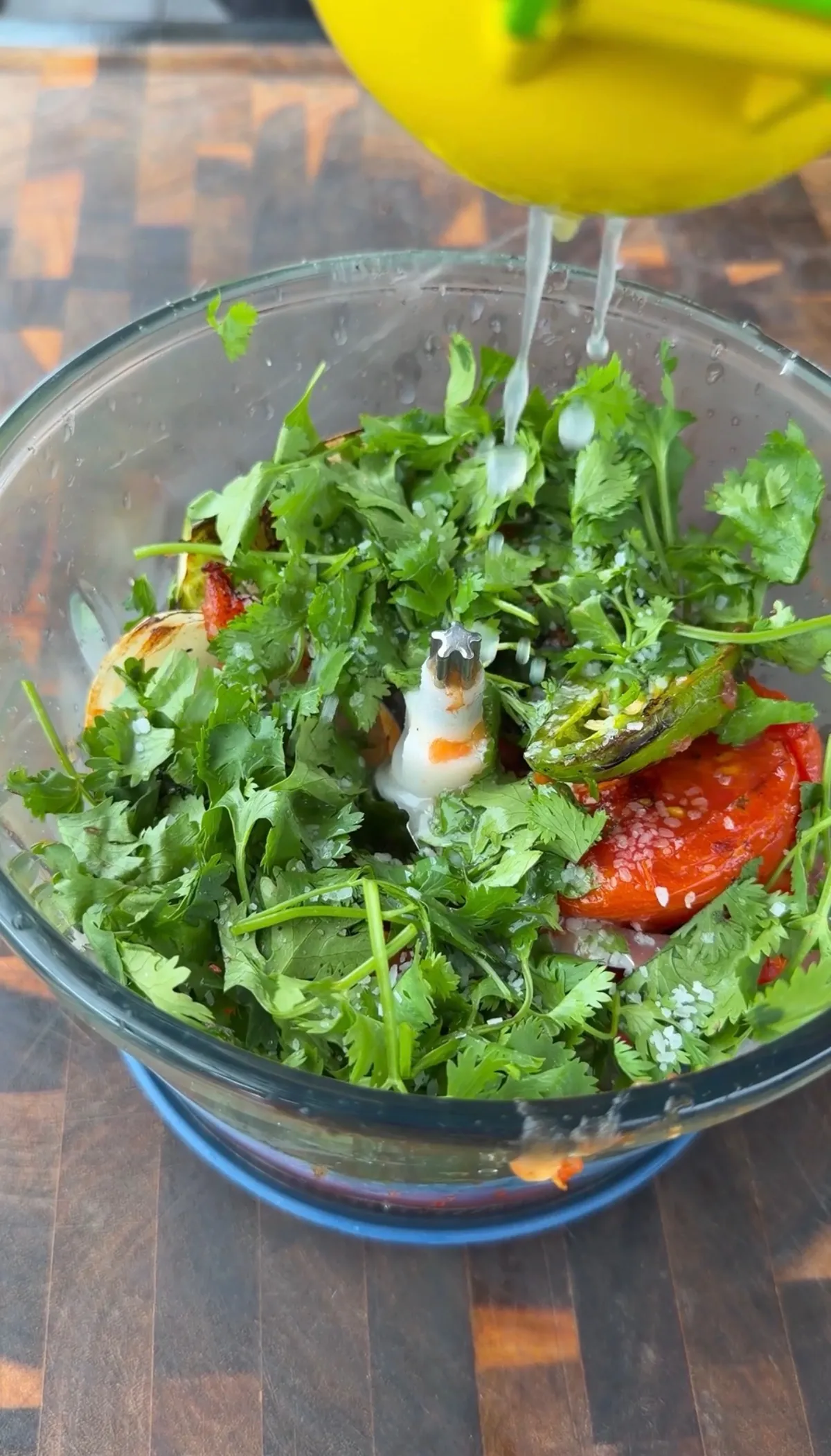 Lime juice being squeezed into blender with roasted tomatoes, jalapeños, onion, garlic, cilantro, and salt for tri tip taco salsa