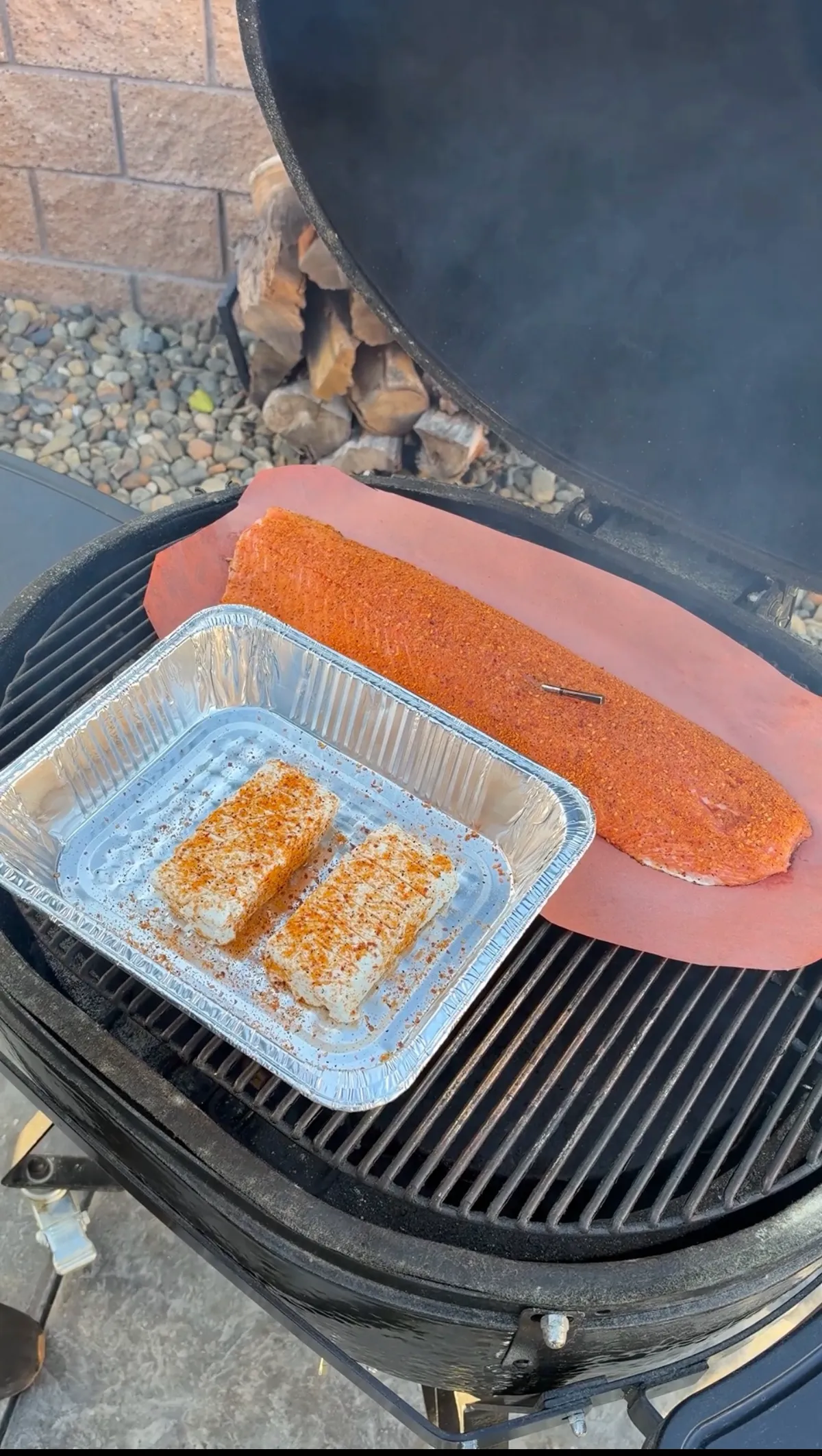 Seasoned salmon fillet on butcher paper and two scored cream cheese blocks in foil tray on smoker at 250°F