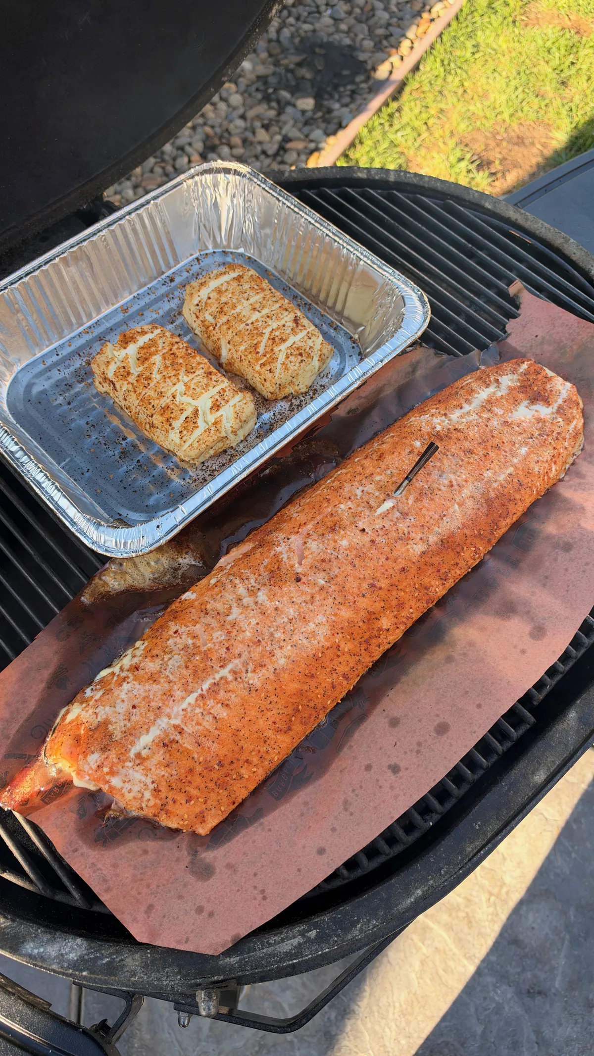 Seasoned salmon fillet and two scored cream cheese blocks smoking on a pellet smoker at 250°F with applewood