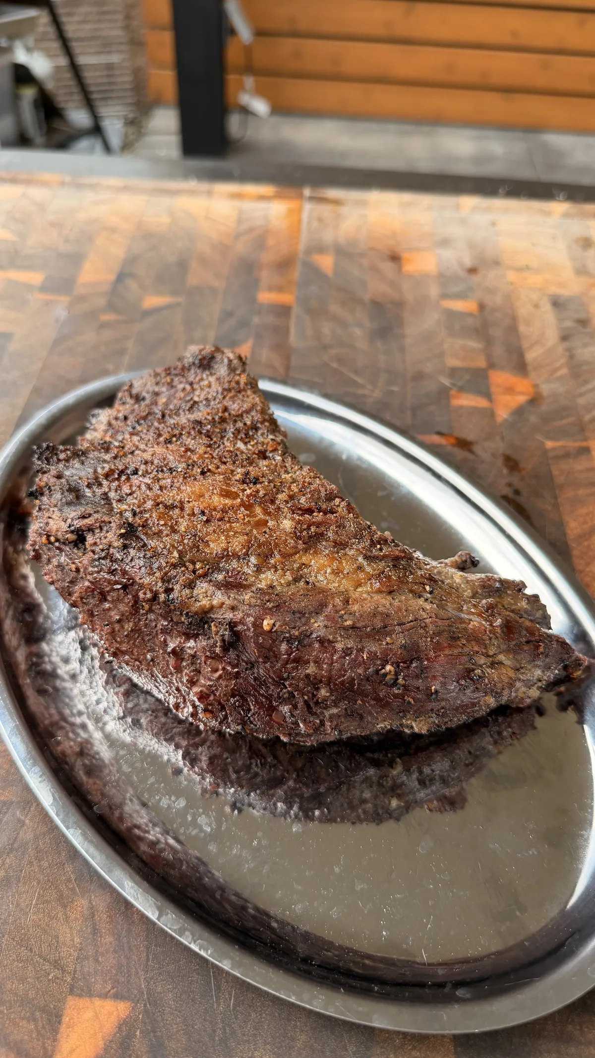 Whole tri-tip seasoned with kosher salt, black pepper, and garlic powder on a silver oval tray, ready to grill