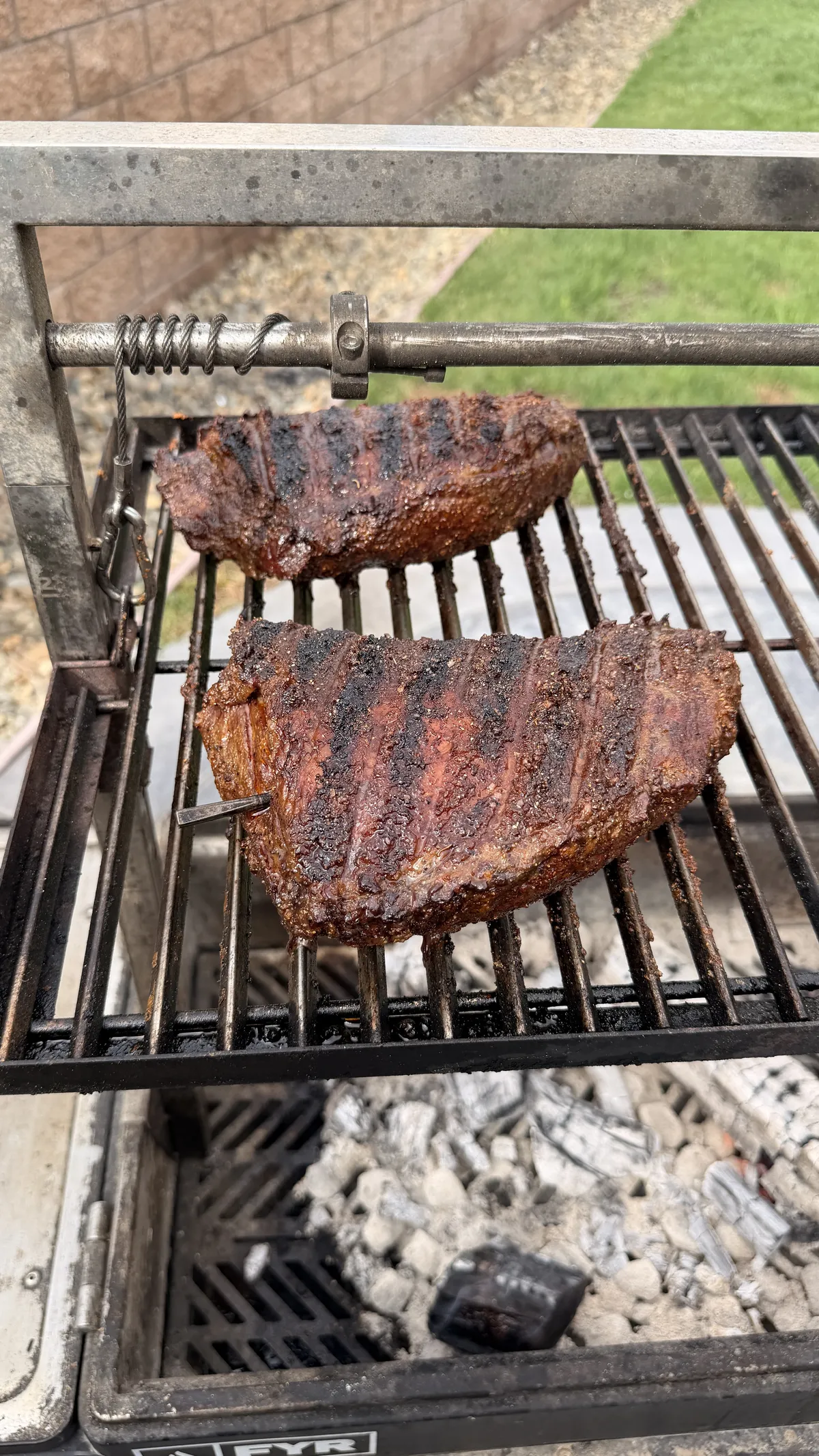 Two seasoned tri-tips with mud rub cooking fat cap down on a Santa Maria charcoal grill with hickory smoke