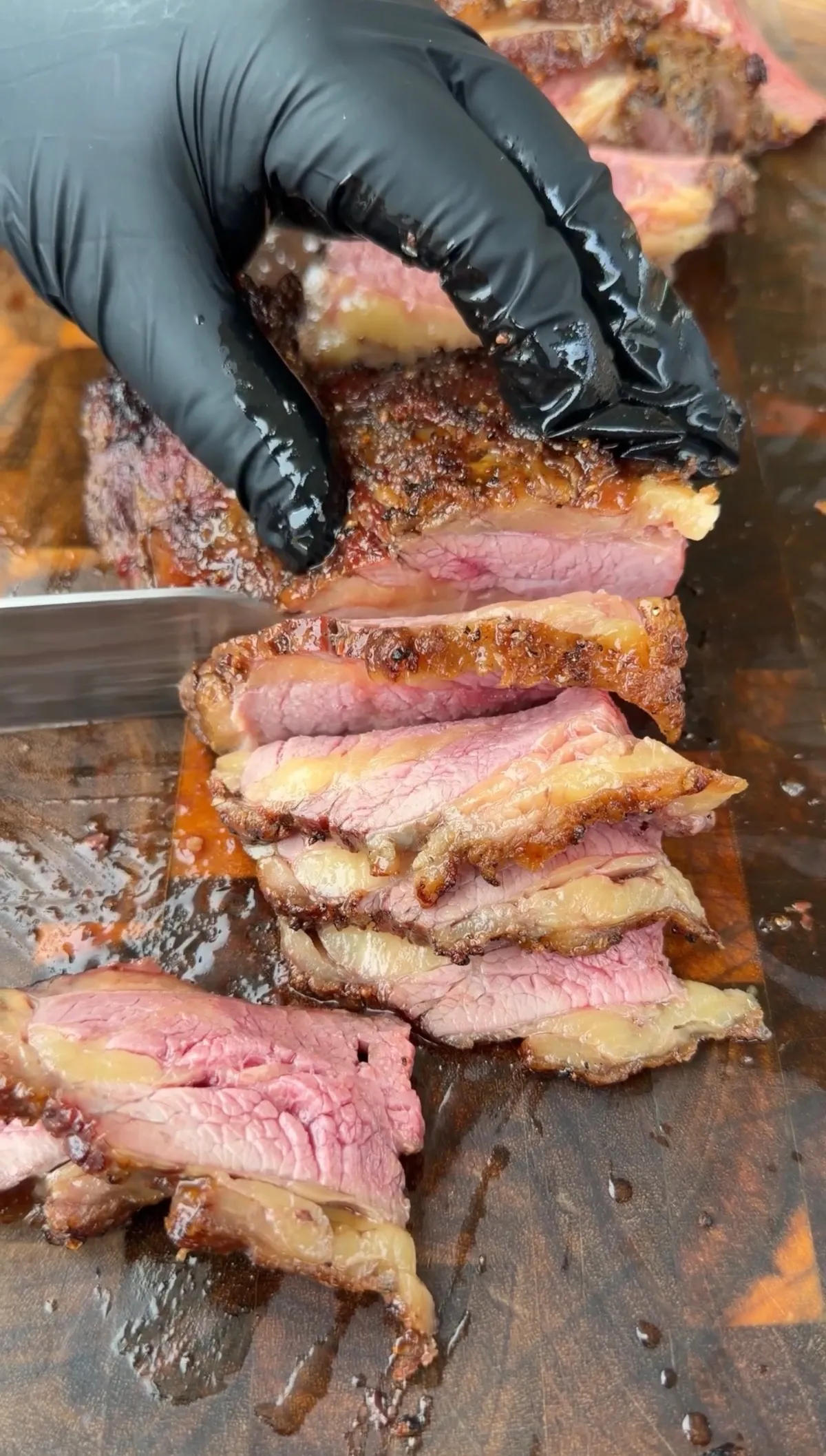 Thinly sliced medium-rare Santa Maria-style tri-tip being cut against the grain on a wooden cutting board