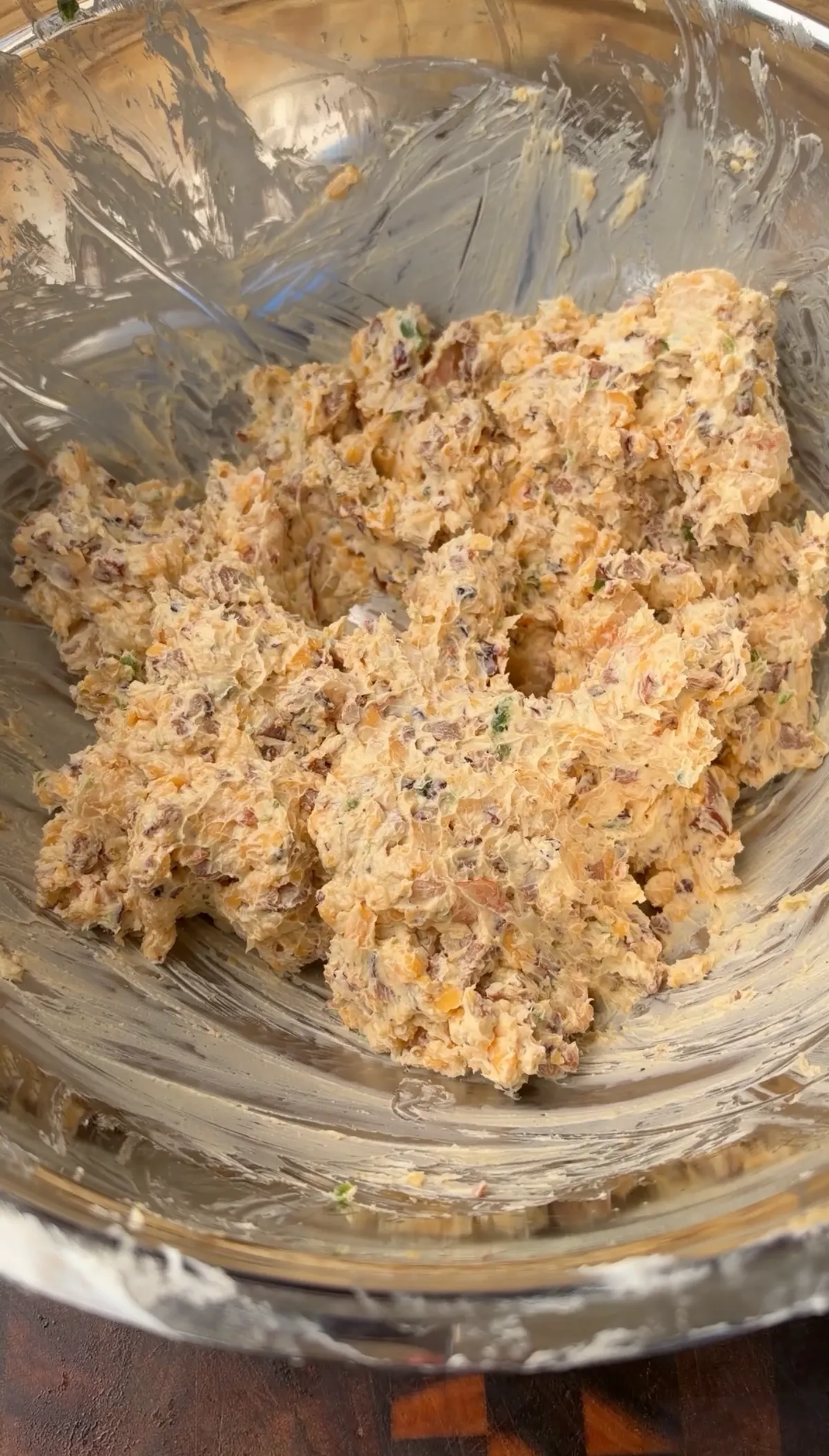 Sausage, shrimp, cream cheese, cheddar, and BBQ seasoning filling mixed in a glass bowl for jalapeño poppers