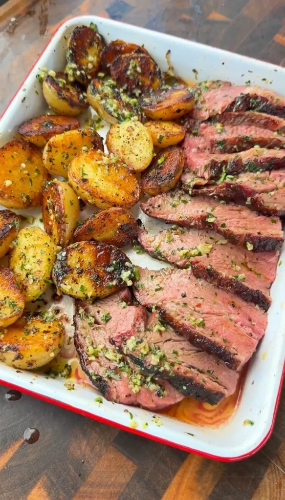 Sliced reverse-seared smoked tri-tip with garlic herb butter and chimichurri alongside crispy roasted lemon pepper potatoes