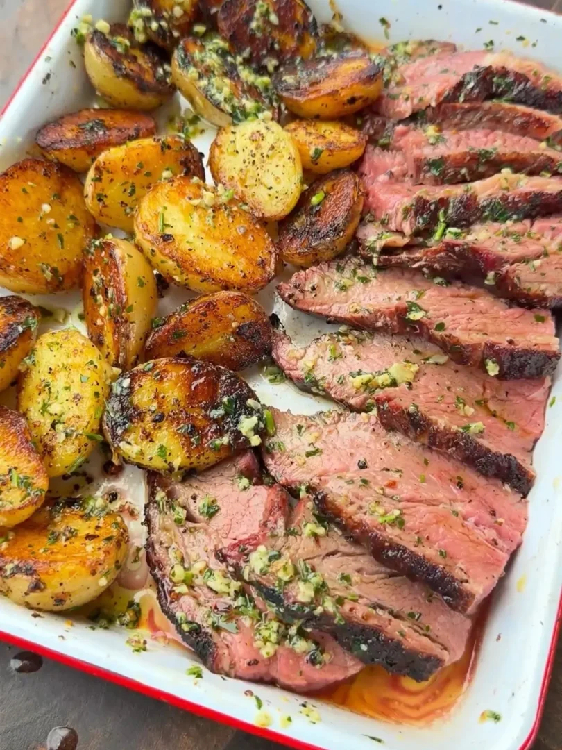Sliced reverse-seared smoked tri-tip with garlic herb butter and chimichurri alongside crispy roasted lemon pepper potatoes