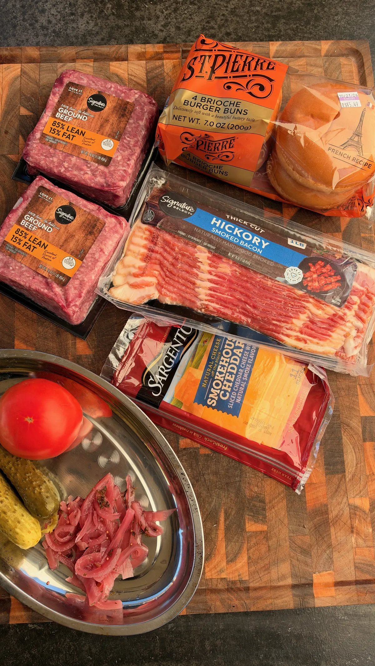 Smoked beer can burger ingredients: 85/15 ground beef, brioche buns, hickory bacon, smokehouse cheddar, pickles, pickled red onions, and tomato