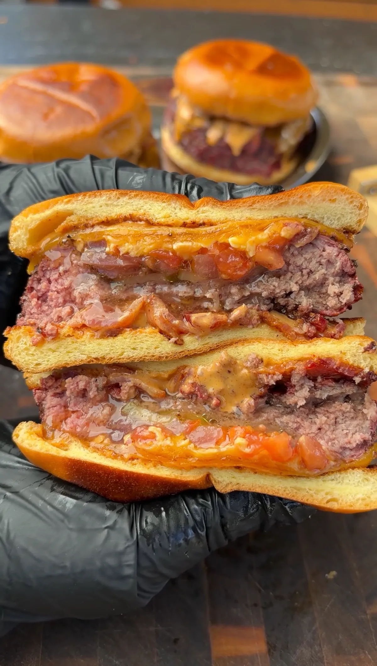 Cross-section of smoked beer can burger stuffed with pickled red onions, cheddar cheese, and burger sauce on brioche bun