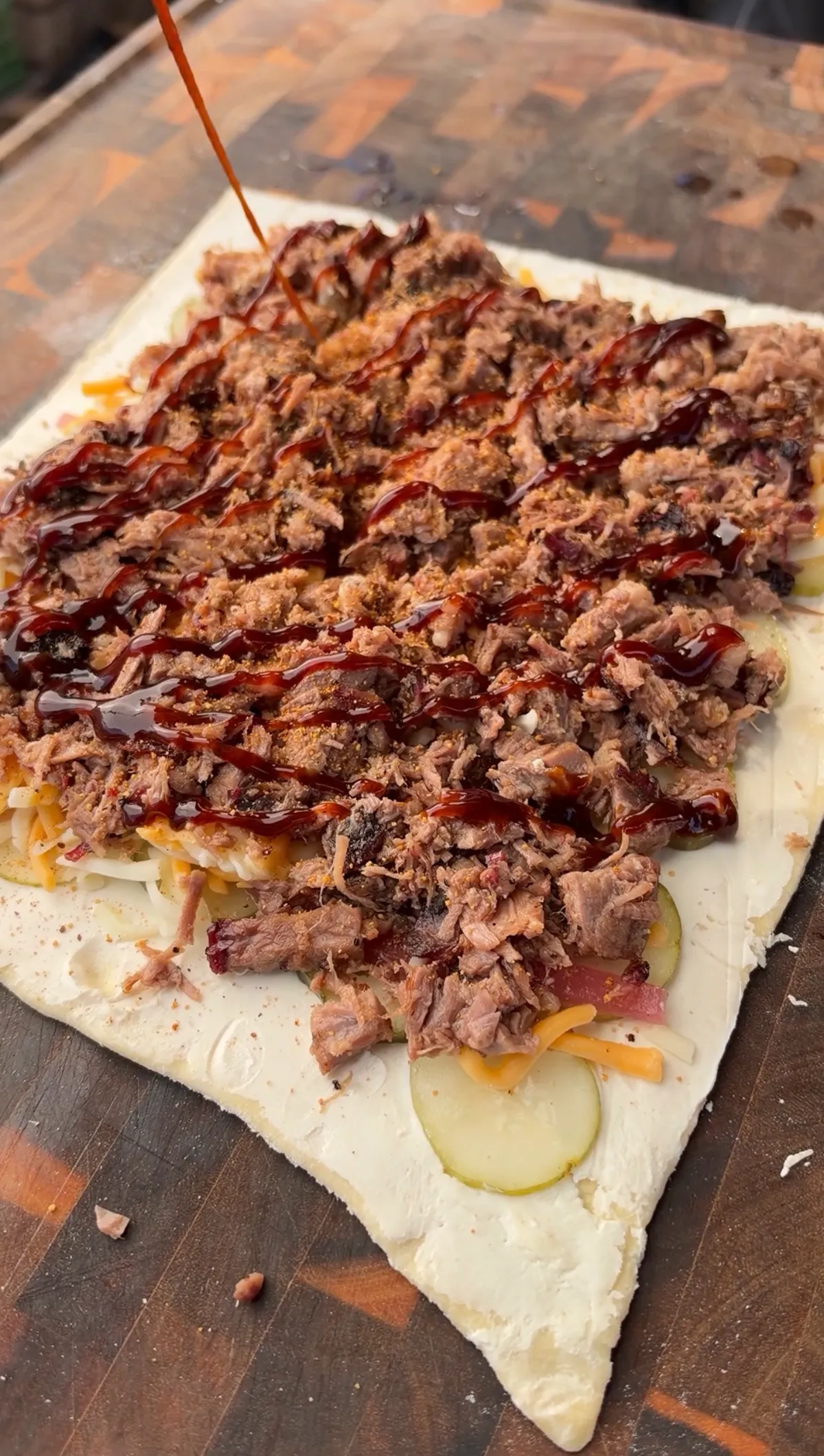 Chopped smoked brisket with cream cheese, pickles, pickled red onions, cheddar, and BBQ sauce on puff pastry