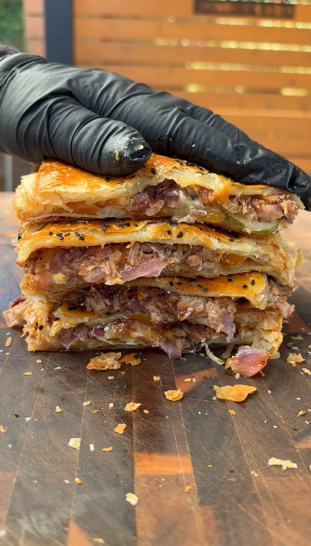 Sliced smoked brisket stuffed hot pocket showing layers of cheddar, pickles, pickled red onions, and BBQ sauce in golden puff pastry