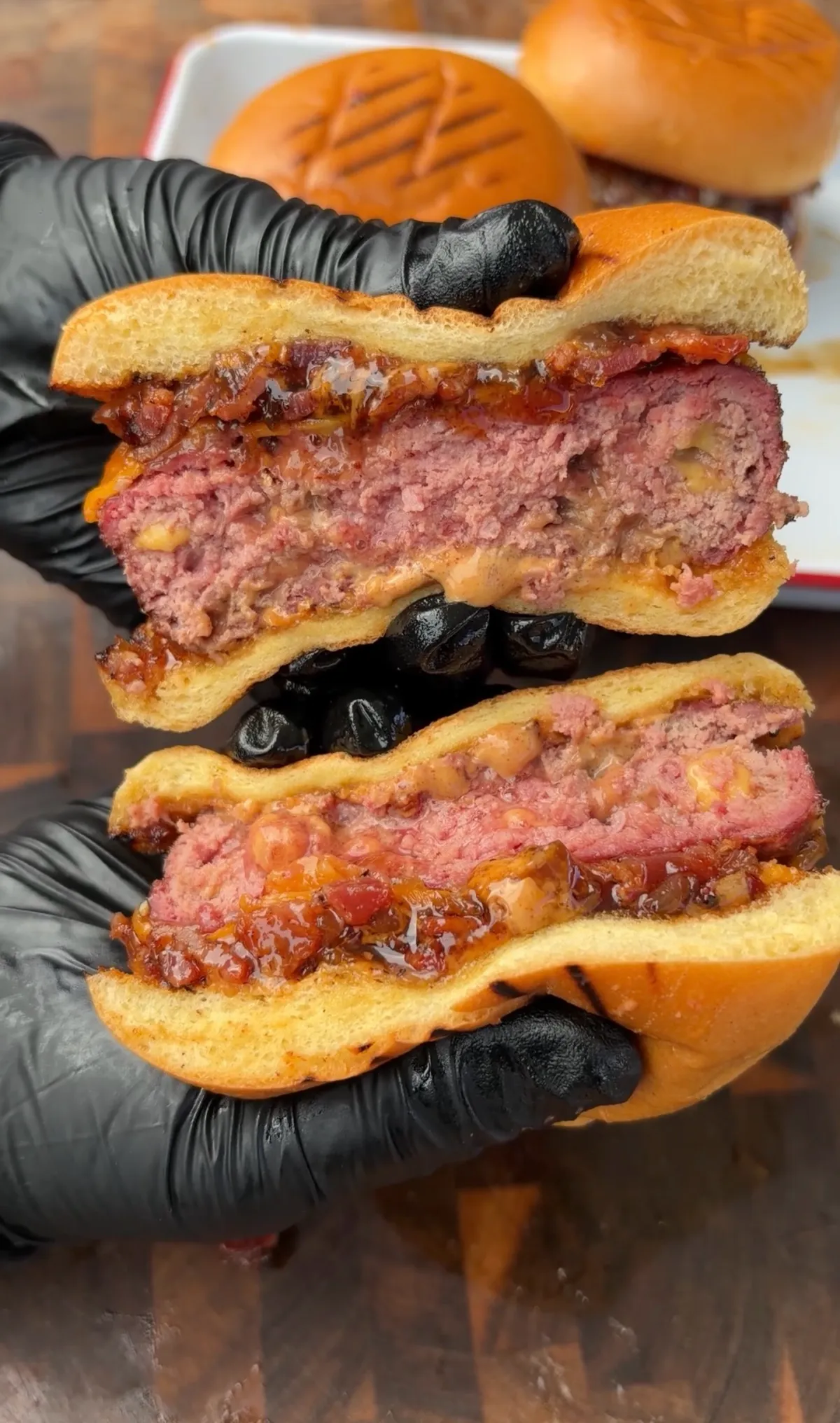 Cross-section of smoked cheddar stuffed burgers with bacon jam and chipotle mayo on toasted brioche buns