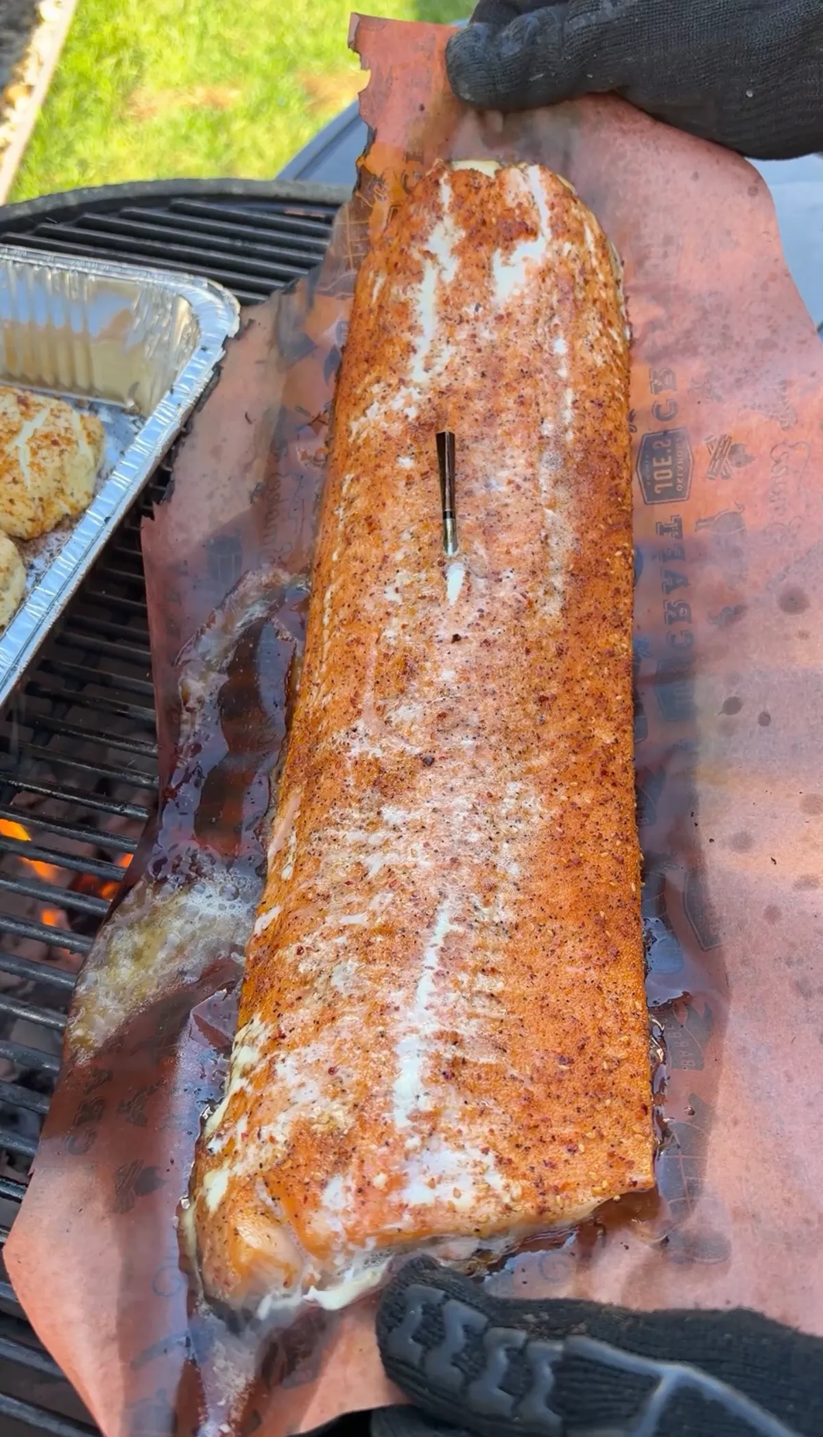 Seasoned 1-lb salmon fillet wrapped in butcher paper with a meat thermometer inserted, smoking at 250°F over applewood