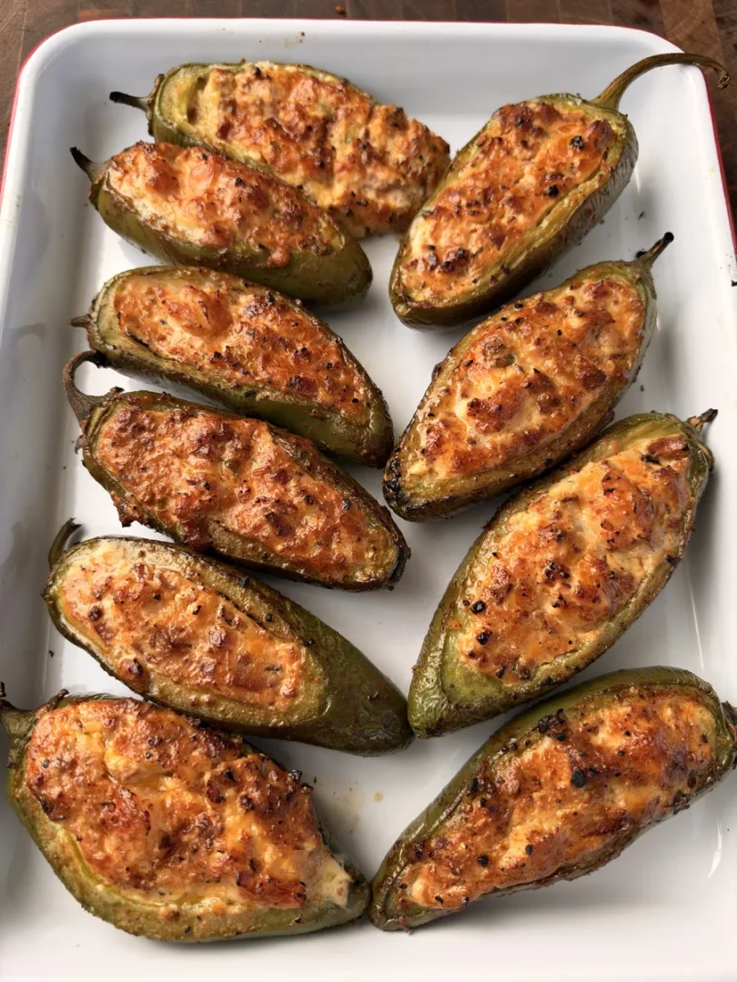 Applewood-smoked sausage and shrimp stuffed jalapeño poppers with melted cheddar on a white platter