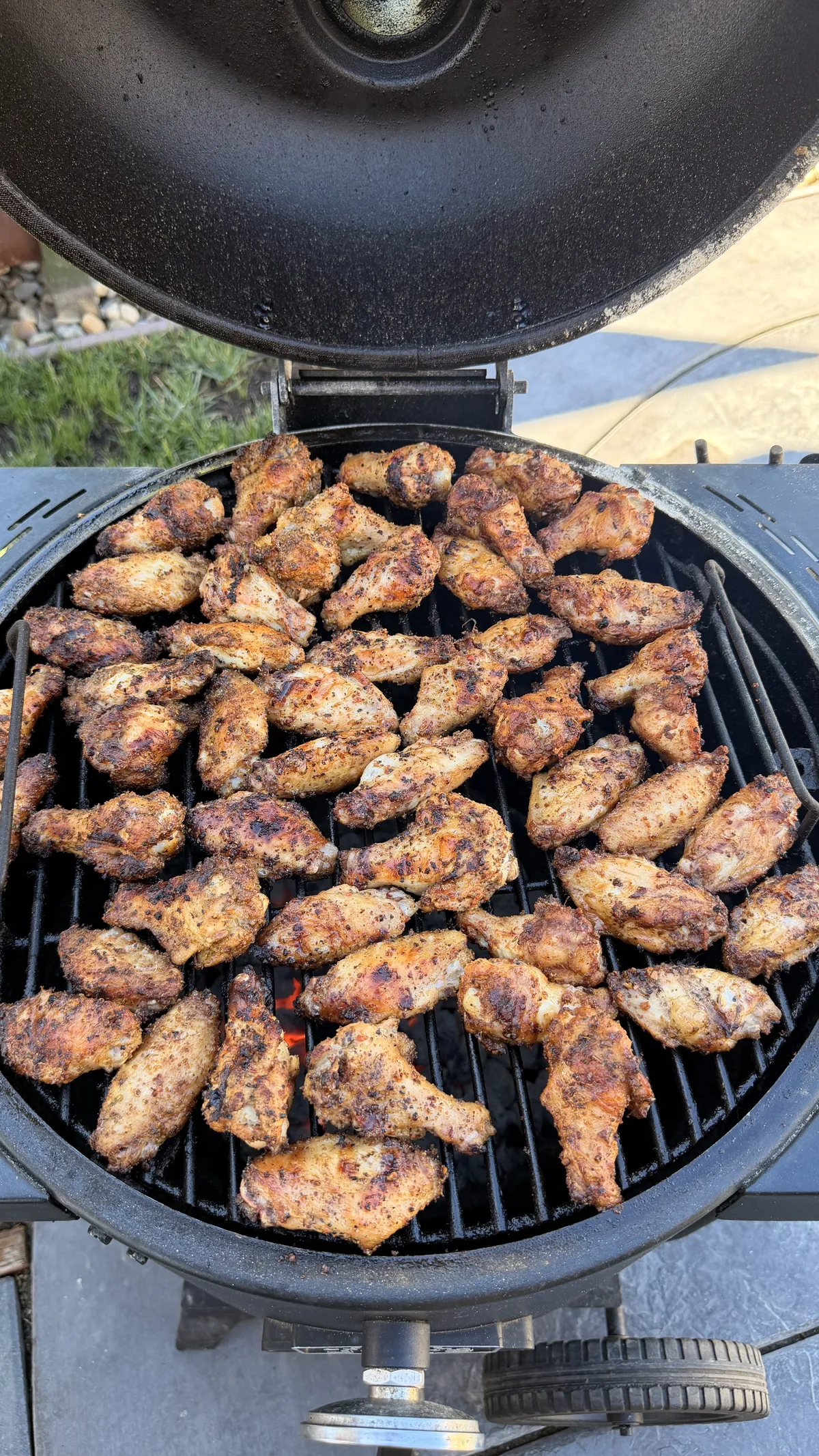 Three-way chicken wings with Cajun, lemon pepper, and Dano's dry rub grilling on a charcoal kamado grill at 350°F